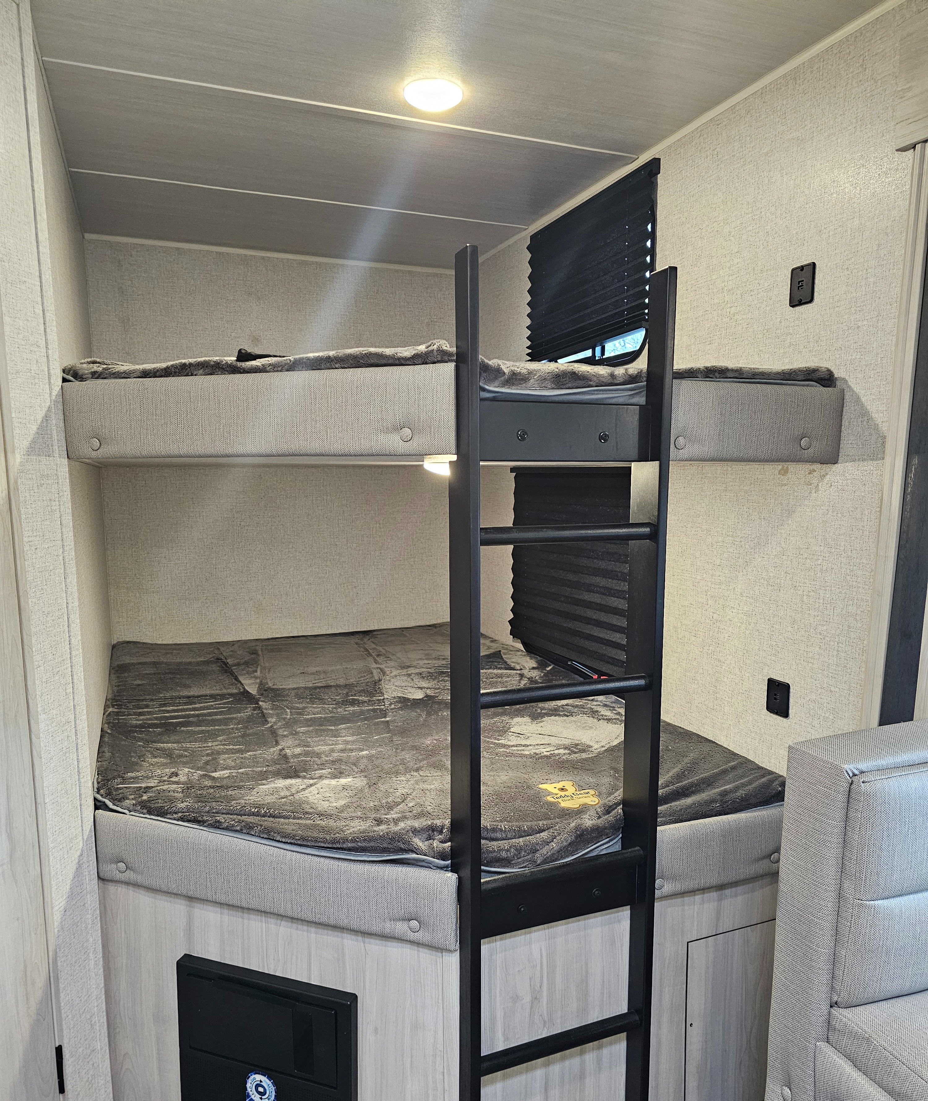 An RV rental interior showing light-colored bunk beds with a ladder, featuring soft bedding.. East to West Della Terra LE 2023