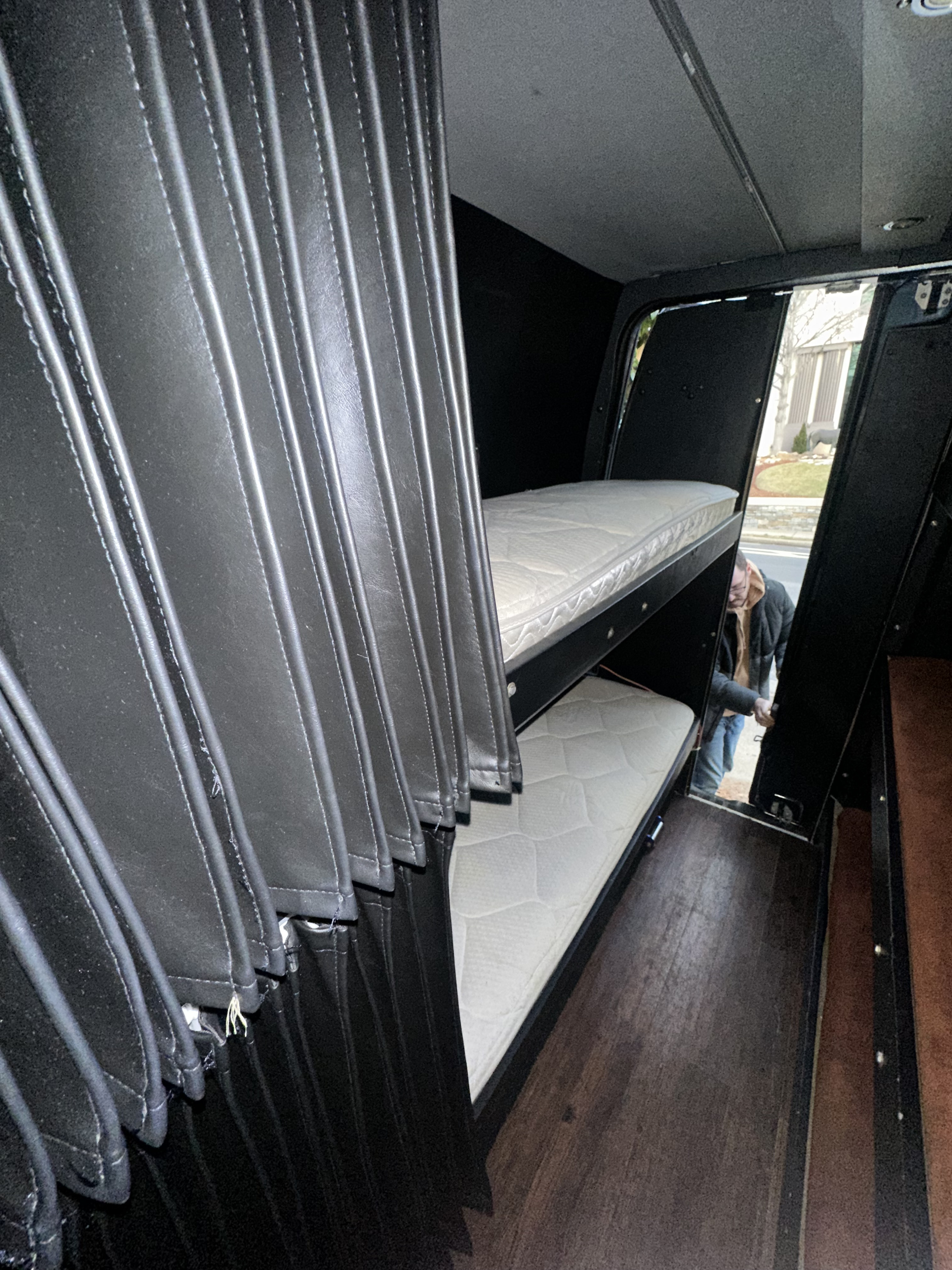 RV rental interior: comfy bunk beds for a cozy sleeping area. A person is by the entrance.. Mercedes 3500 2013