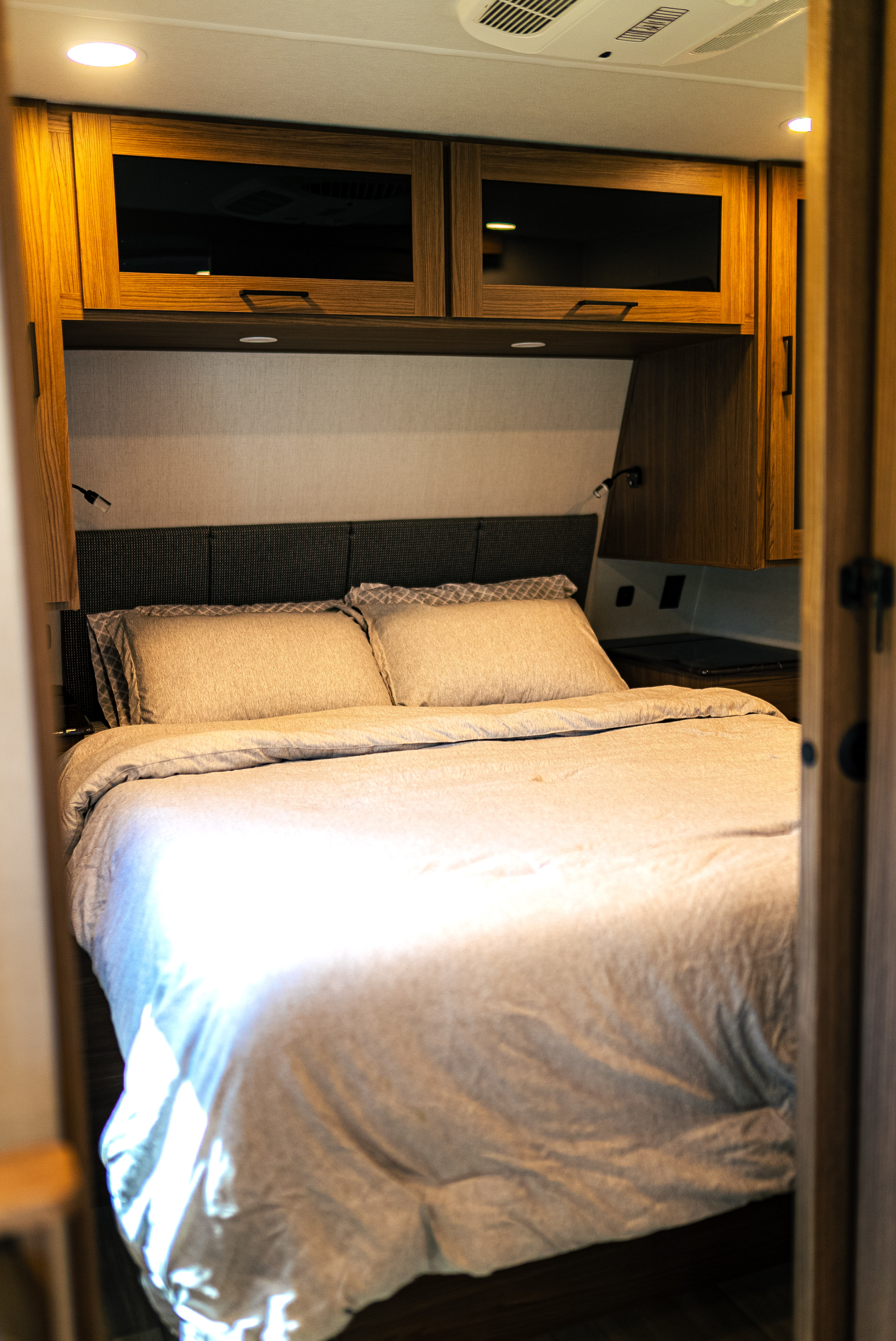 Cozy RV rental bedroom with a comfortable bed, overhead cabinets, and reading lights. Perfect for your next adventure.. Alliance Delta 281BH 2024