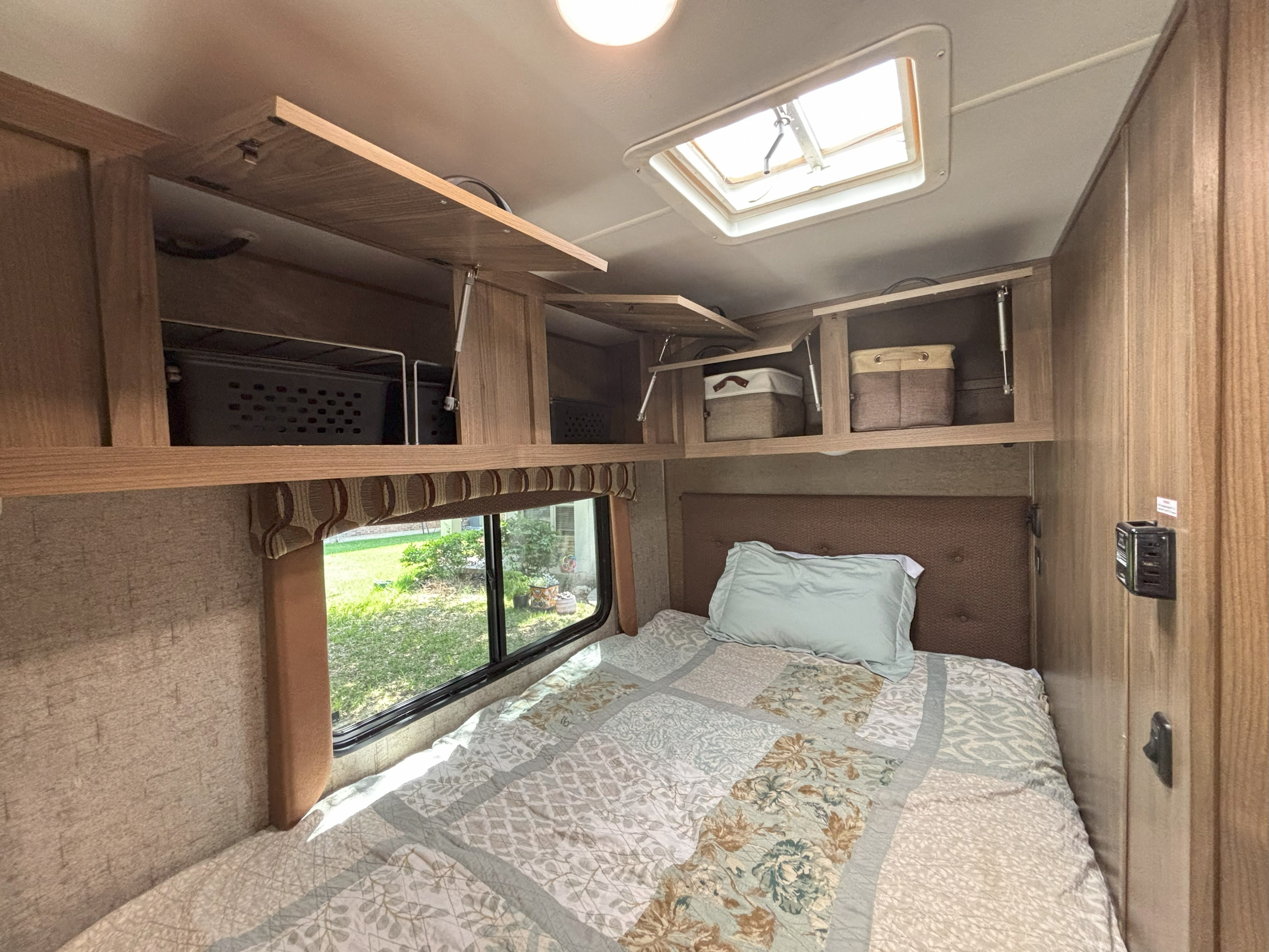RV rental bedroom interior with overhead cabinets, comfortable bed, and a scenic window view through the window.. Forest River Coachmen Freelander Micro 2018