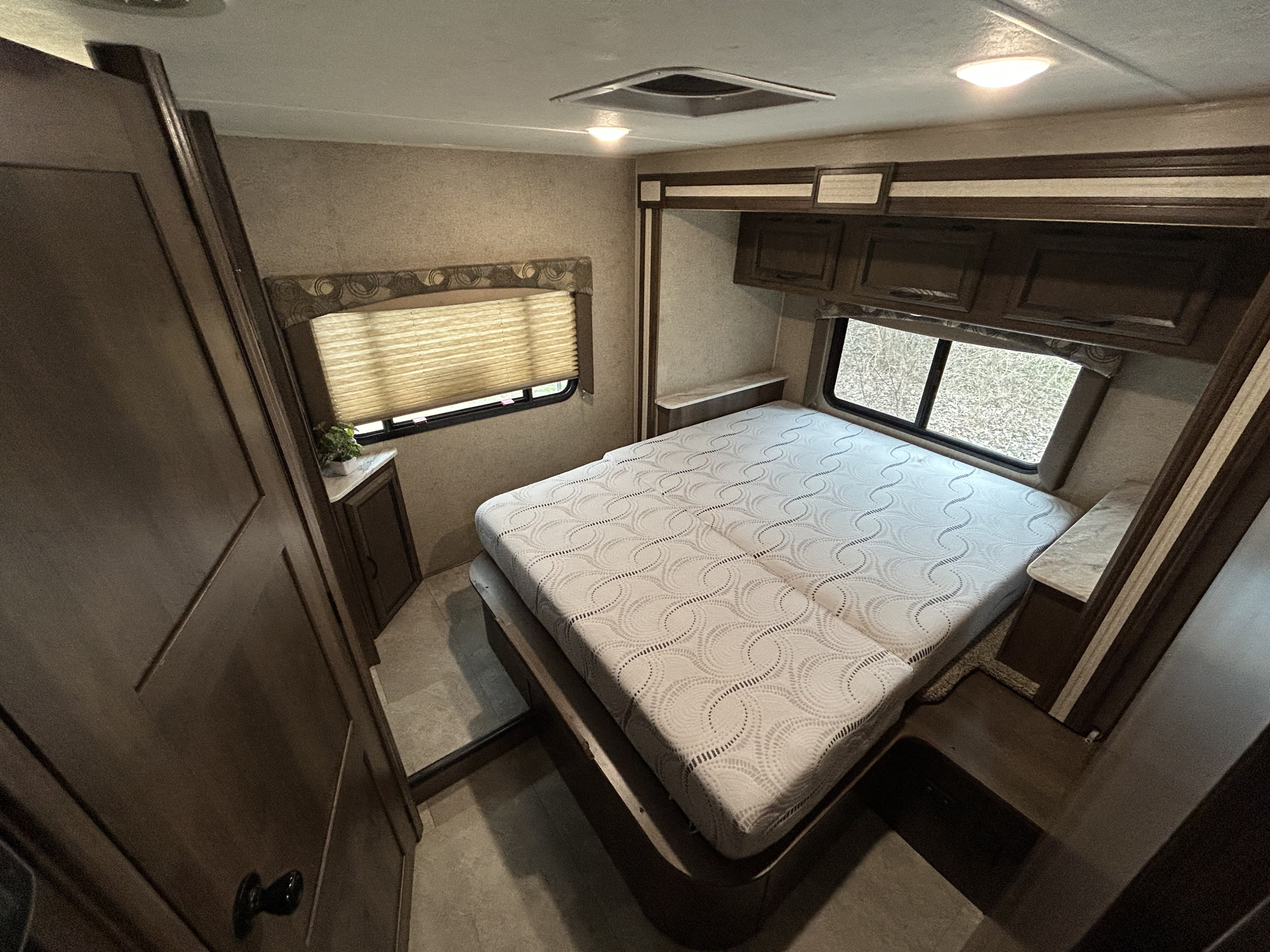 Spacious RV rental bedroom featuring a comfortable bed, ample storage, and large windows, ideal for travel.. Coachman Freelander 26DS 2019