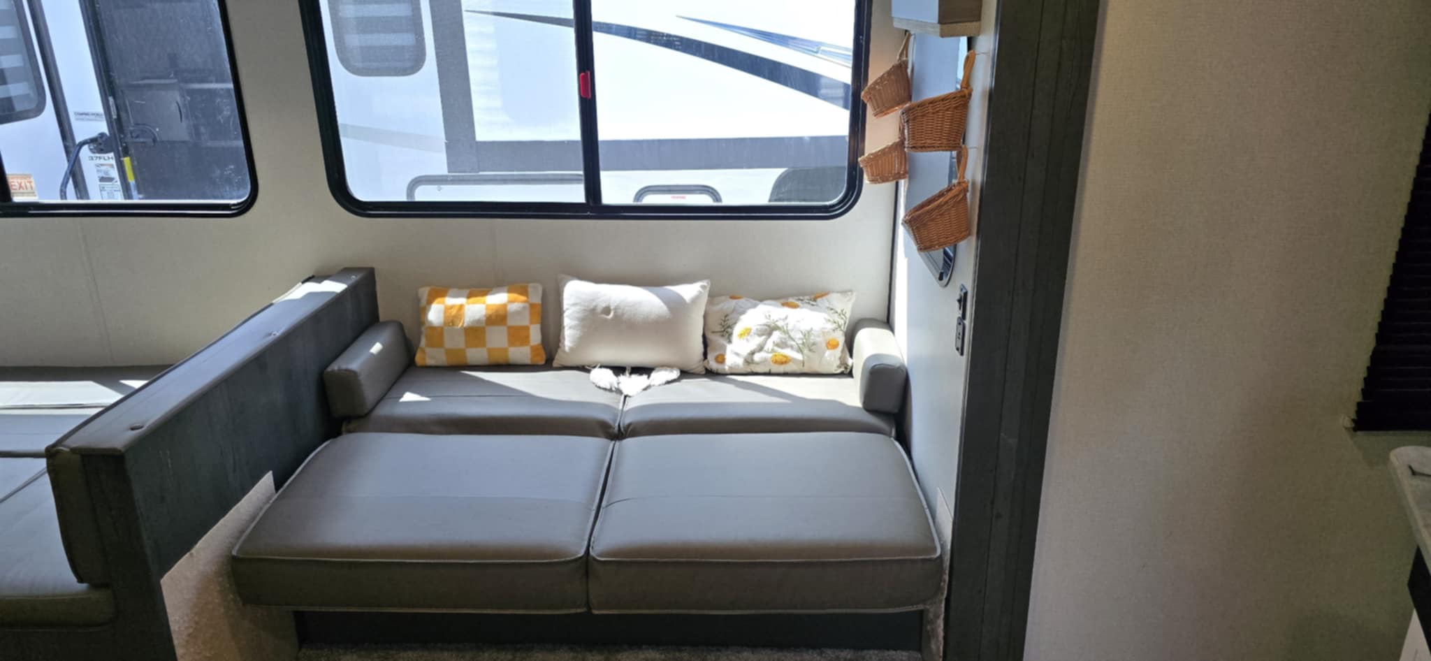 RV rental: Cozy gray sofa converts to a bed with colorful pillows, framed by a window & woven storage baskets.. Keystone Hideout 2022