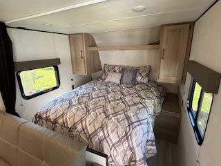 RV rental bedroom with comfy queen bed, side windows, and ample storage for travel & camping.. Keystone RV Coleman 23B 2025