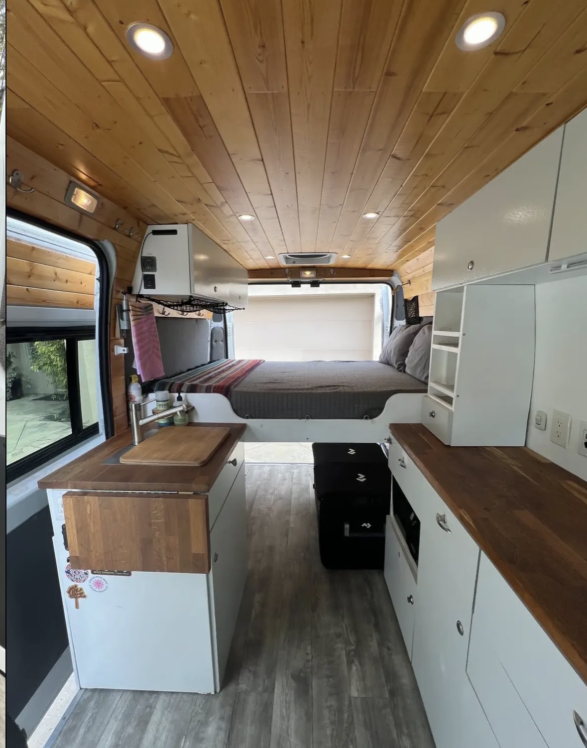 Step inside this well-equipped RV rental camper van, featuring a compact kitchen, comfortable bed, & warm wood accents.. Dodge 1500 2018