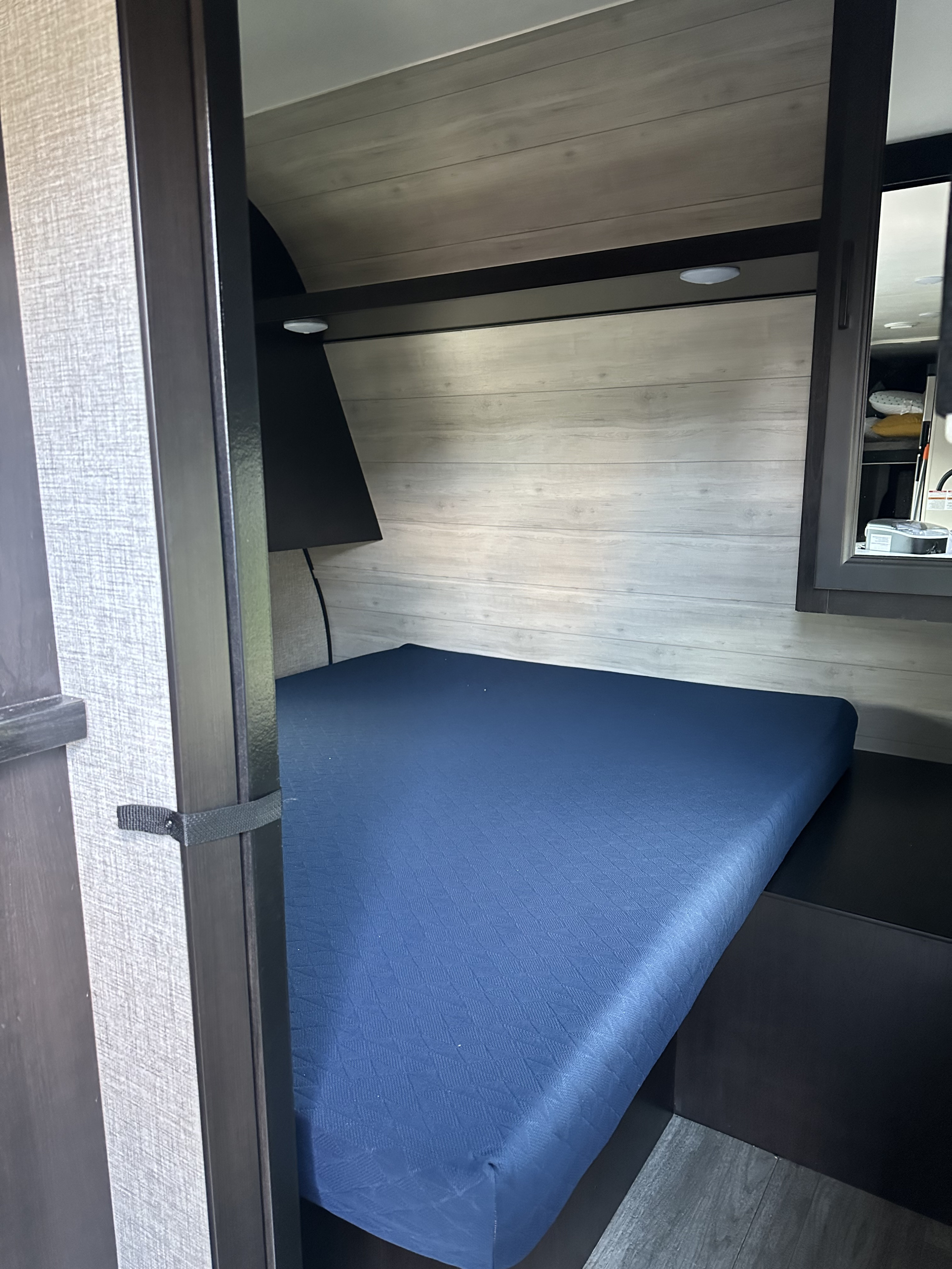 Cozy RV rental sleeping area with a blue mattress, modern wood-look walls, built-in cabinetry, and task lighting.. Jayco Jay Flight SLX 2022