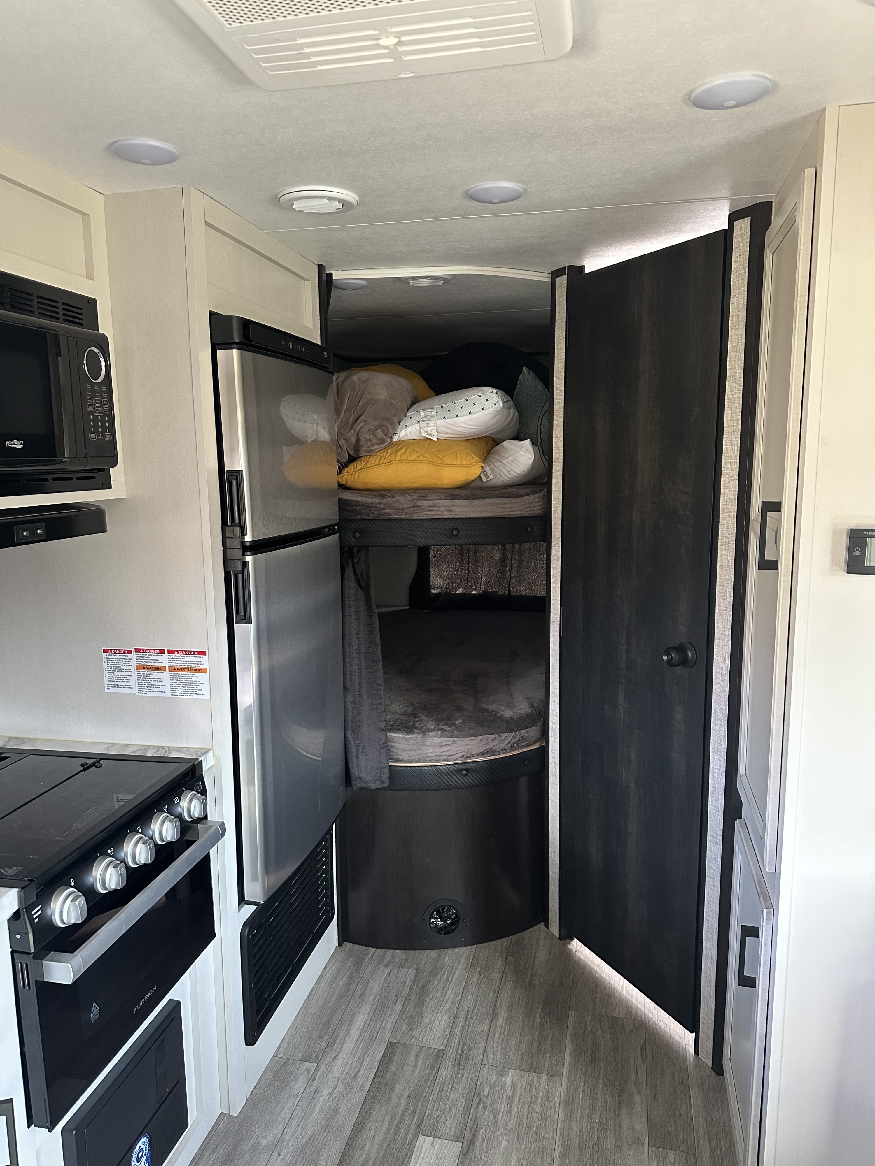 Inside this RV rental, discover a modern kitchen with stove, microwave, and fridge, plus bunk beds with pillows.. Jayco Jay Flight SLX 2022