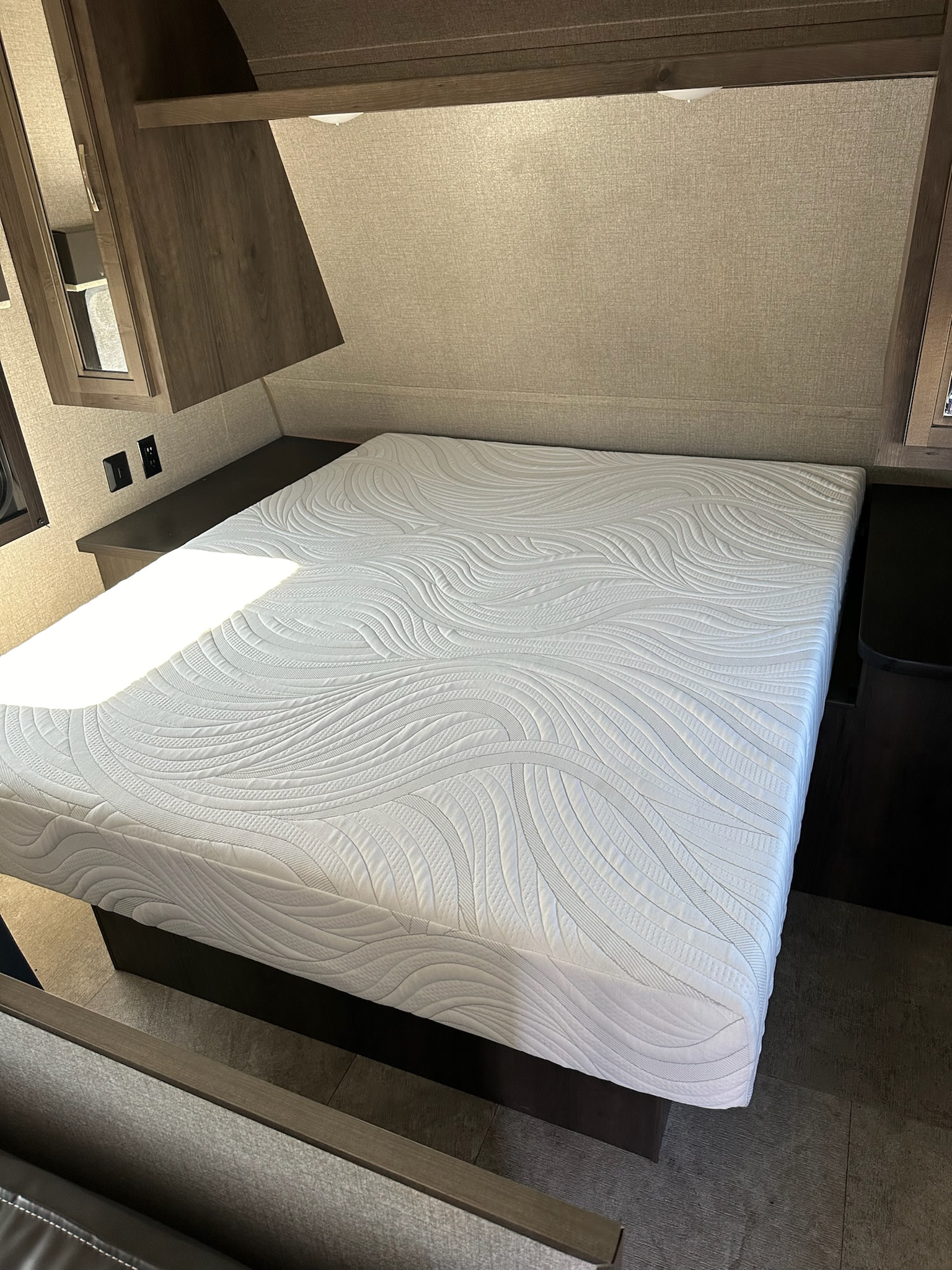 Clean RV rental bedroom featuring a comfortable white mattress, overhead cabinets, and bedside outlets. Ready for your trip!. Jayco Jay Flight SLX 2021
