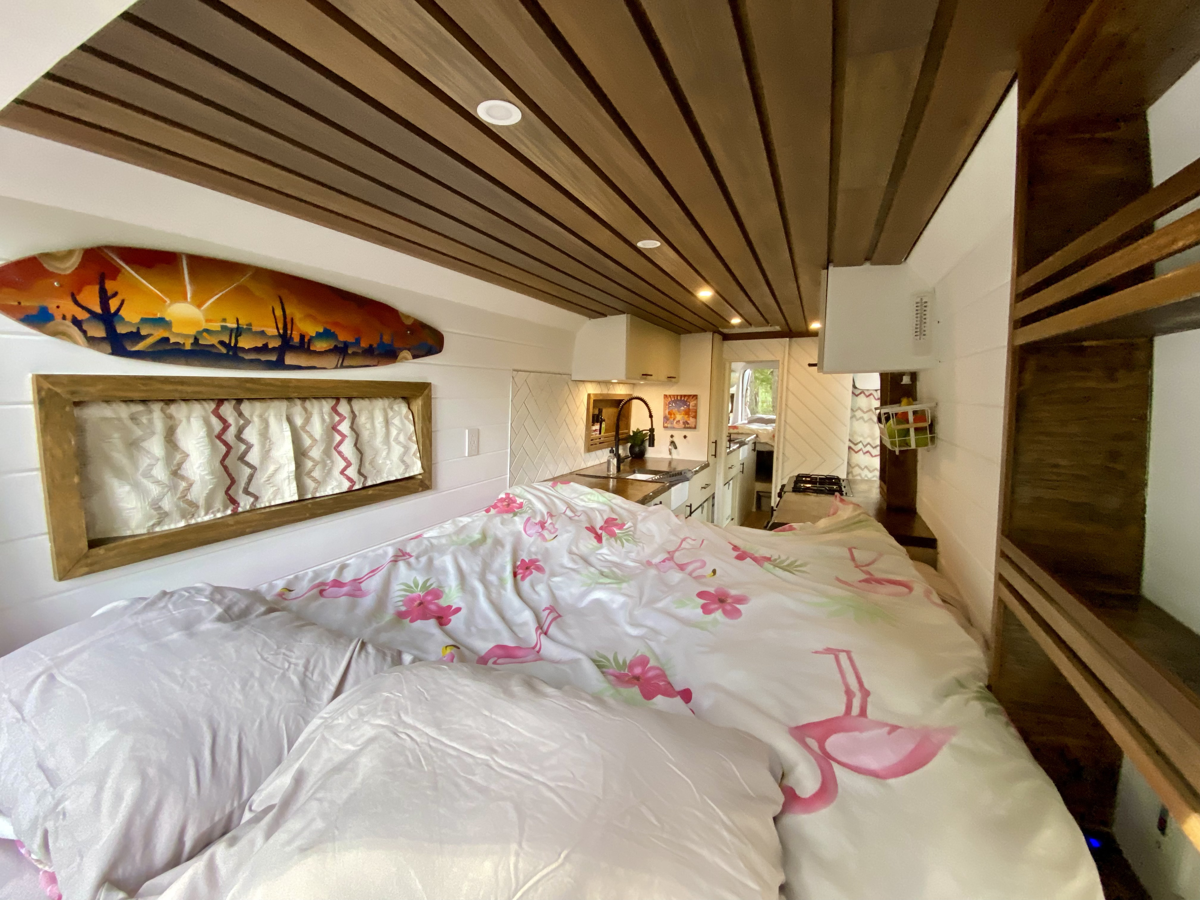 Inside this chic RV rental, enjoy a comfy bed with vibrant flamingo bedding, a well-equipped kitchen, and warm wood ceiling.. Ram Promaster 2018