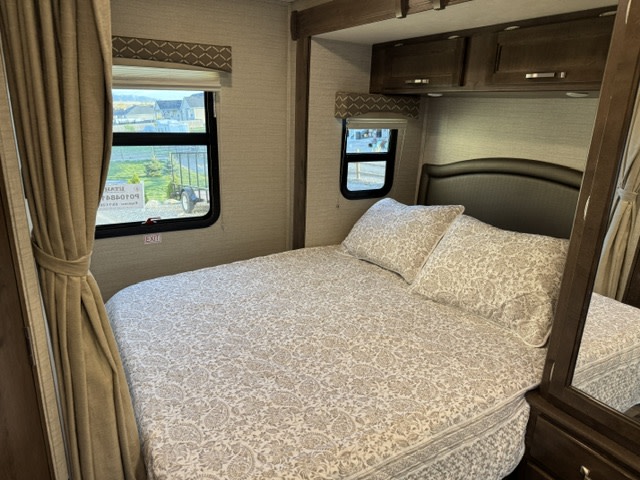 Comfortable RV rental bedroom with a cozy bed, overhead storage, and windows providing outdoor views.. Jayco Melbourne 2020