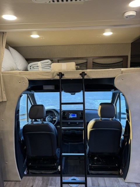 This RV rental's interior features a front cab with driver & passenger seats below an accessible overhead bunk bed & ladder.. Jayco Melbourne 2020
