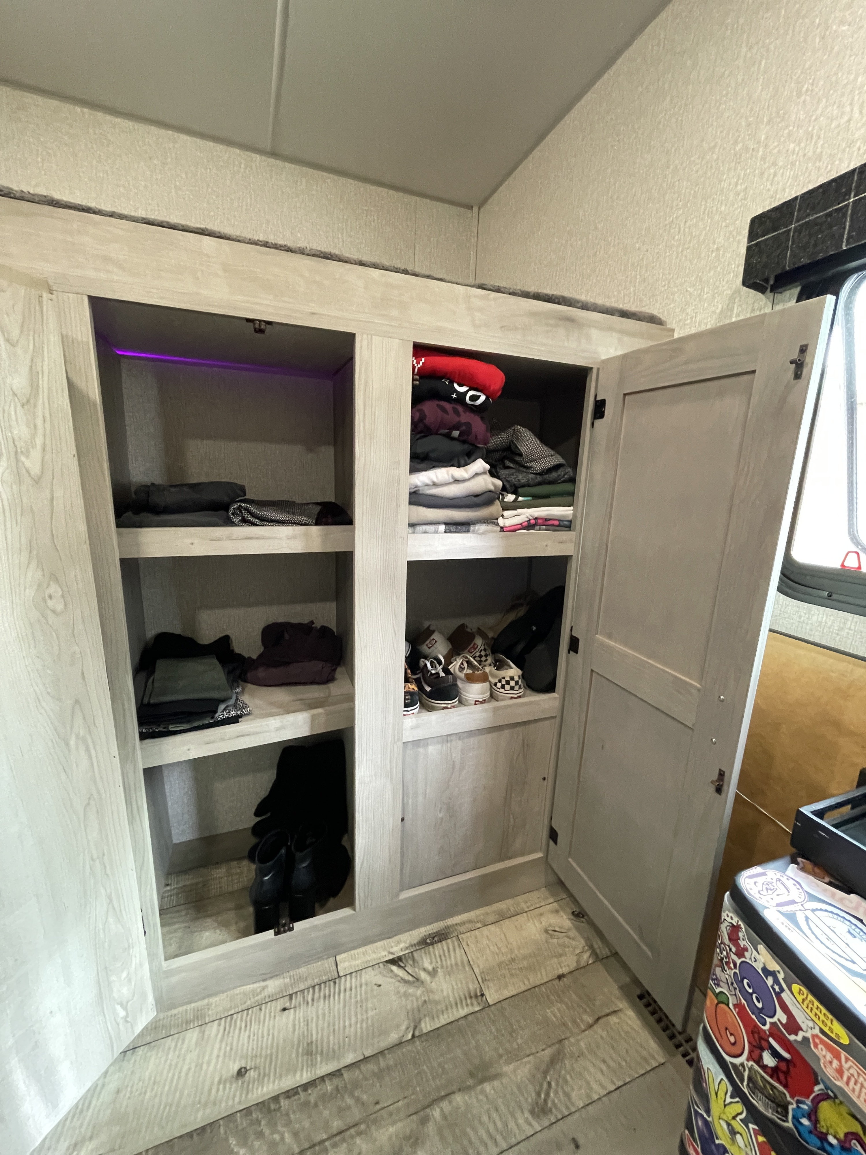 Organized RV rental closet with clothes and shoes, featuring useful shelving and purple accent lighting.. K-Z Manufacturing Other 2022