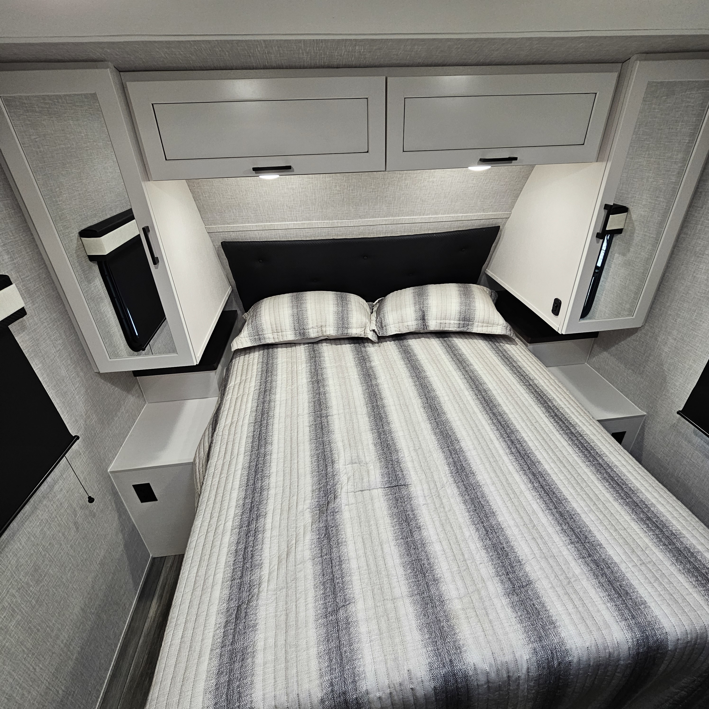 Cozy RV rental bedroom with modern overhead storage, a striped bed, and compact design for comfortable travel.. Jayco Jay Feather 24bh 2025