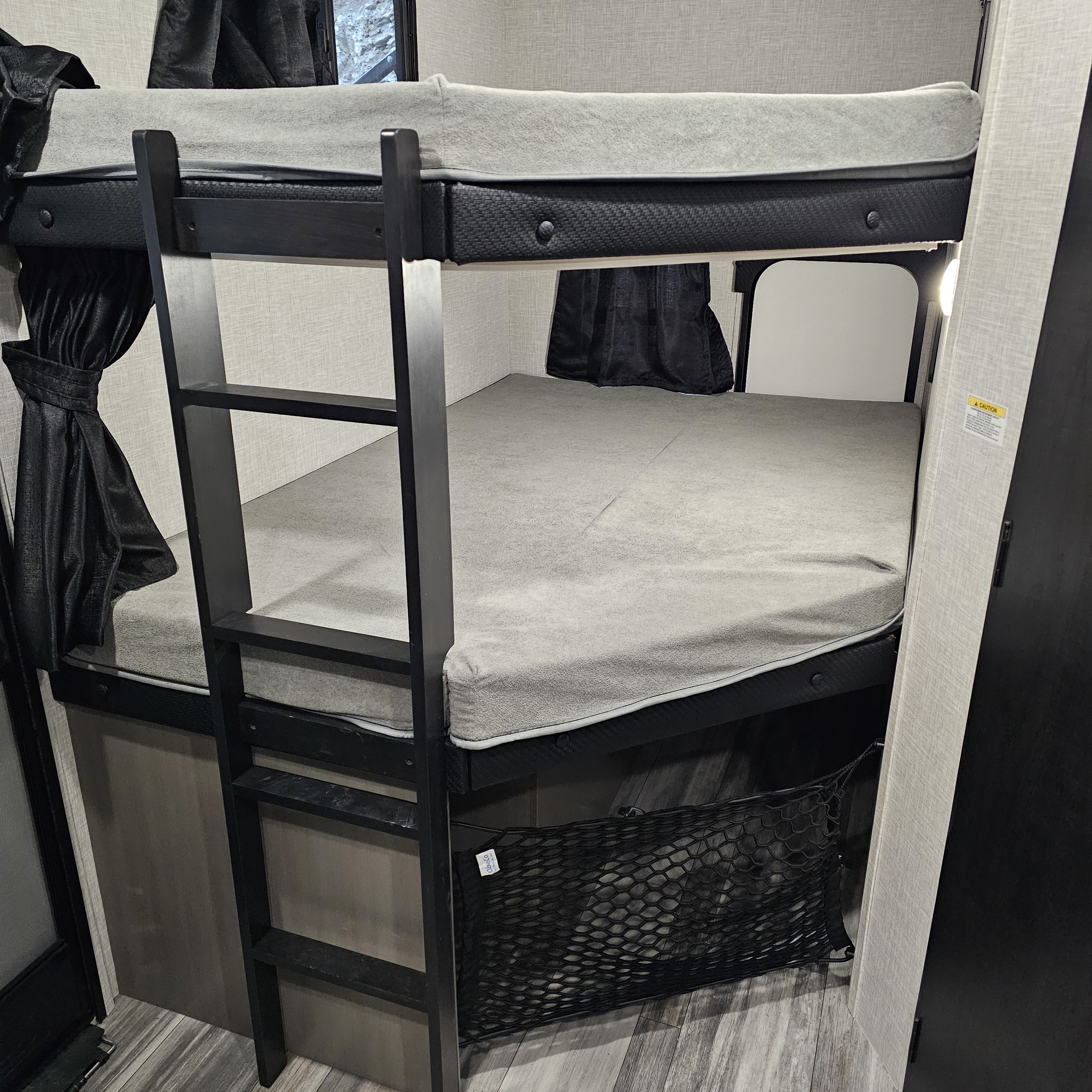 Inside an RV rental: Compact bunk beds with ladder, gray mattresses, and a storage net below.. Jayco Jay Feather 24bh 2025