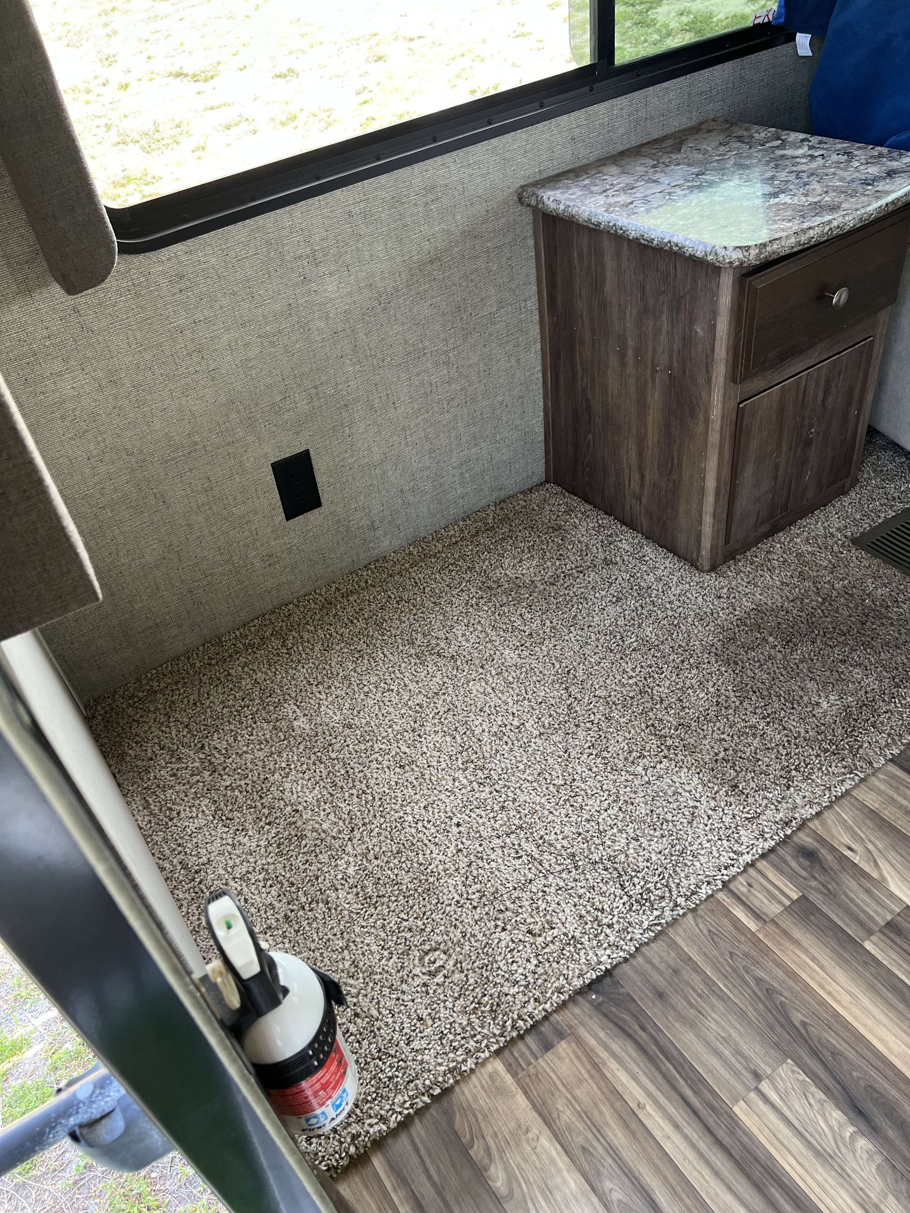 RV rental interior with a nightstand, window, outlet, carpet, laminate flooring, and fire extinguisher.. Keystone RV Cougar 2017