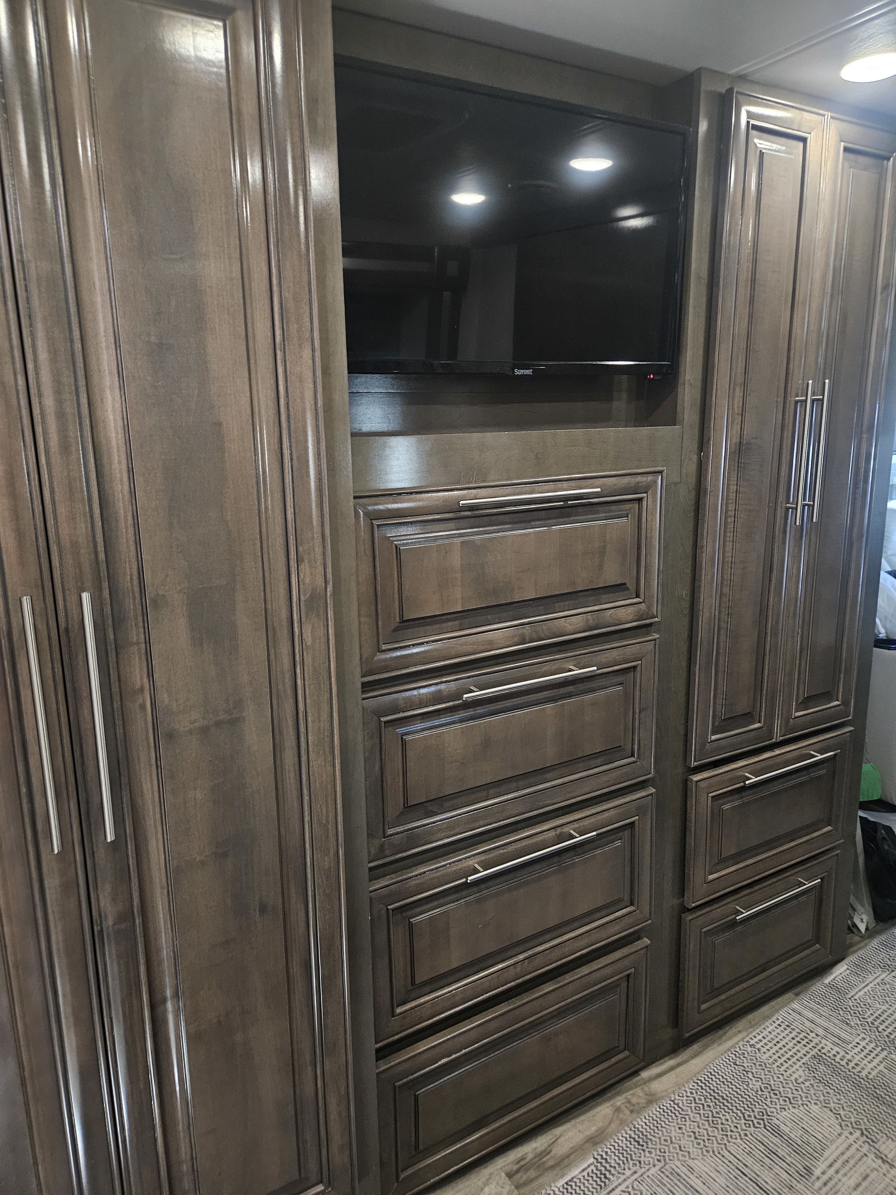 This RV rental features a built-in entertainment and storage unit with a TV, multiple drawers, and tall wood cabinets.. Forest River Georgetown 2022
