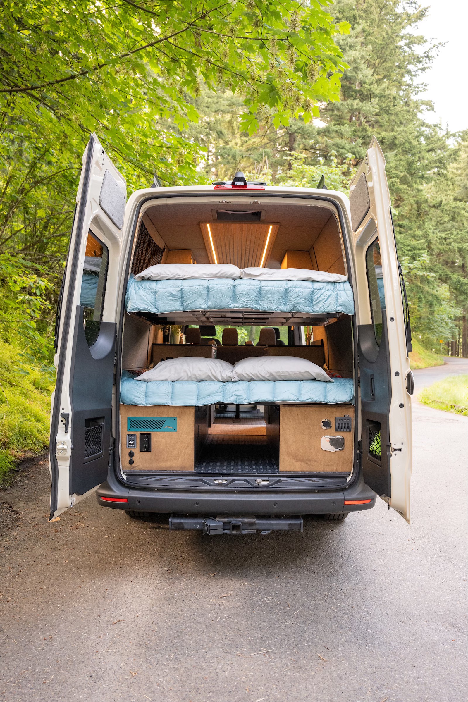 Rear view of an rv rental camper van, showcasing a custom-built interior with two cozy bunk beds and wood finishes.. Mercedes-Benz Sprinter 2021