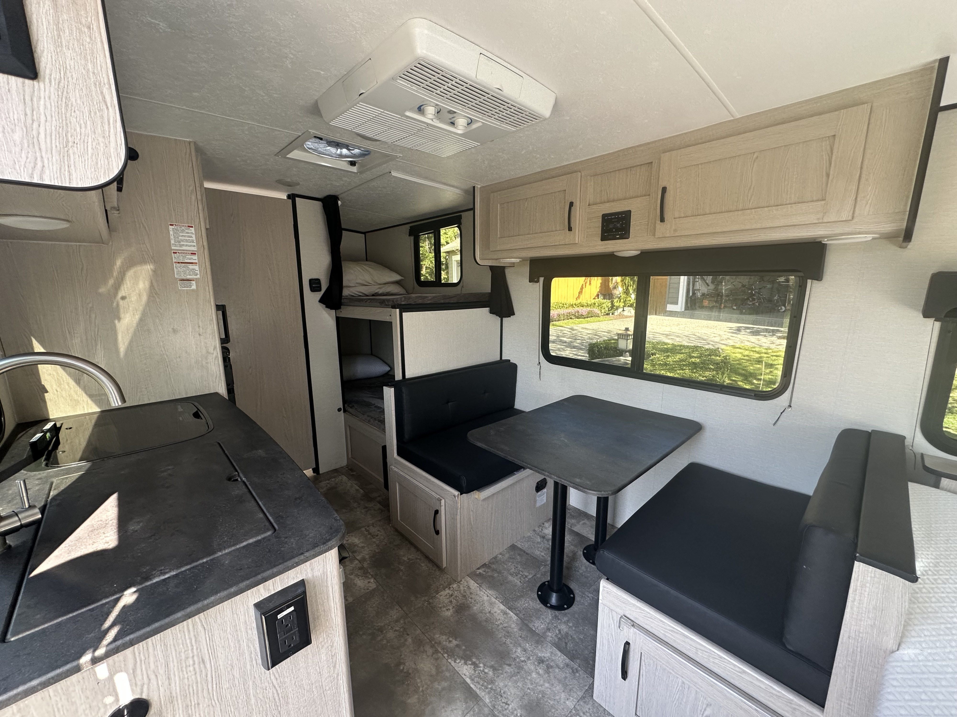 Compact RV rental interior featuring a kitchenette, dinette, and bunk beds, designed for comfortable travel.. Apex Nano 2023