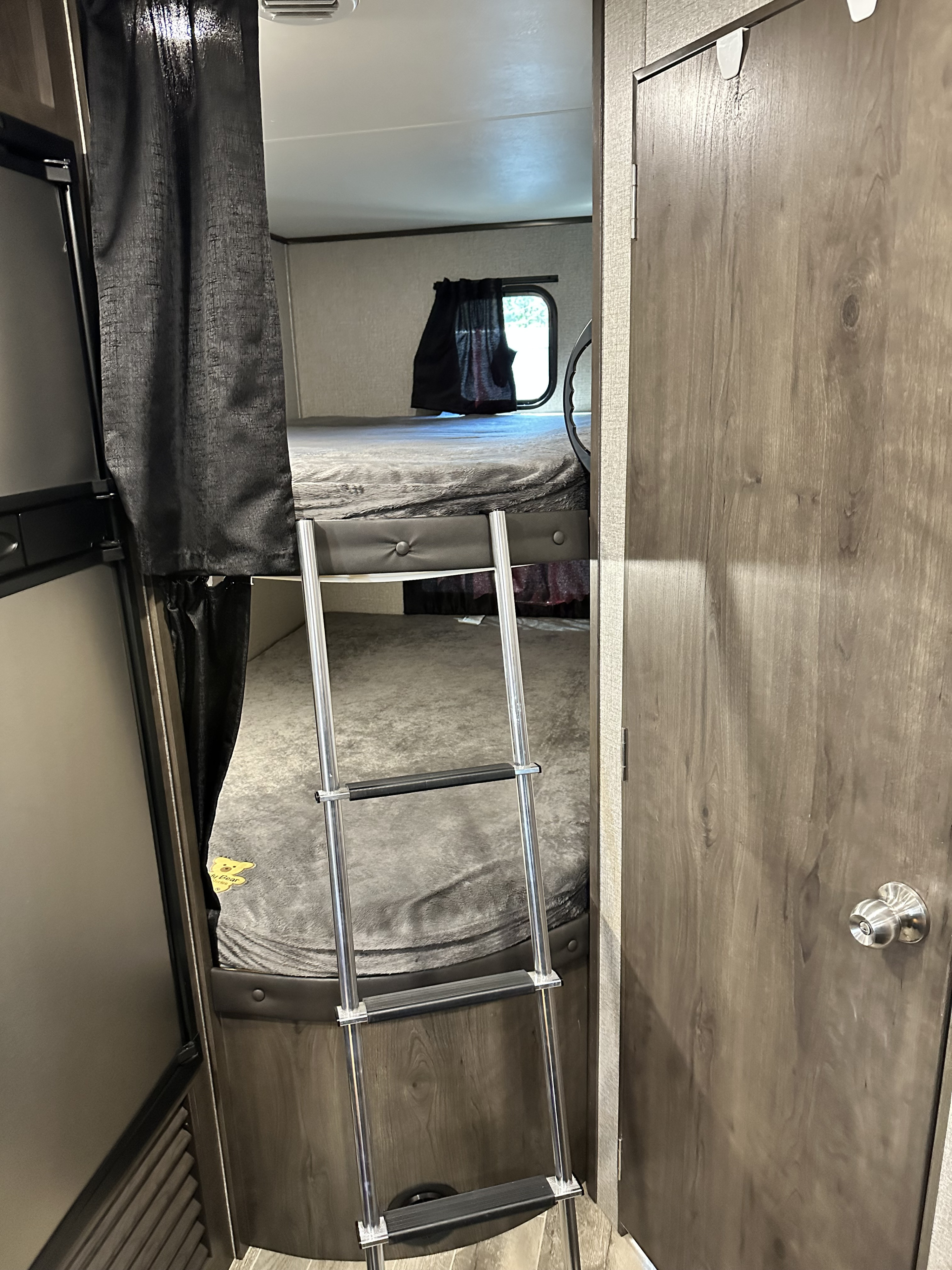 Explore this RV rental's sleeping area, featuring comfortable bunk beds with grey bedding, a ladder, and privacy curtains.. Jayco Jay Flight SLX 2021