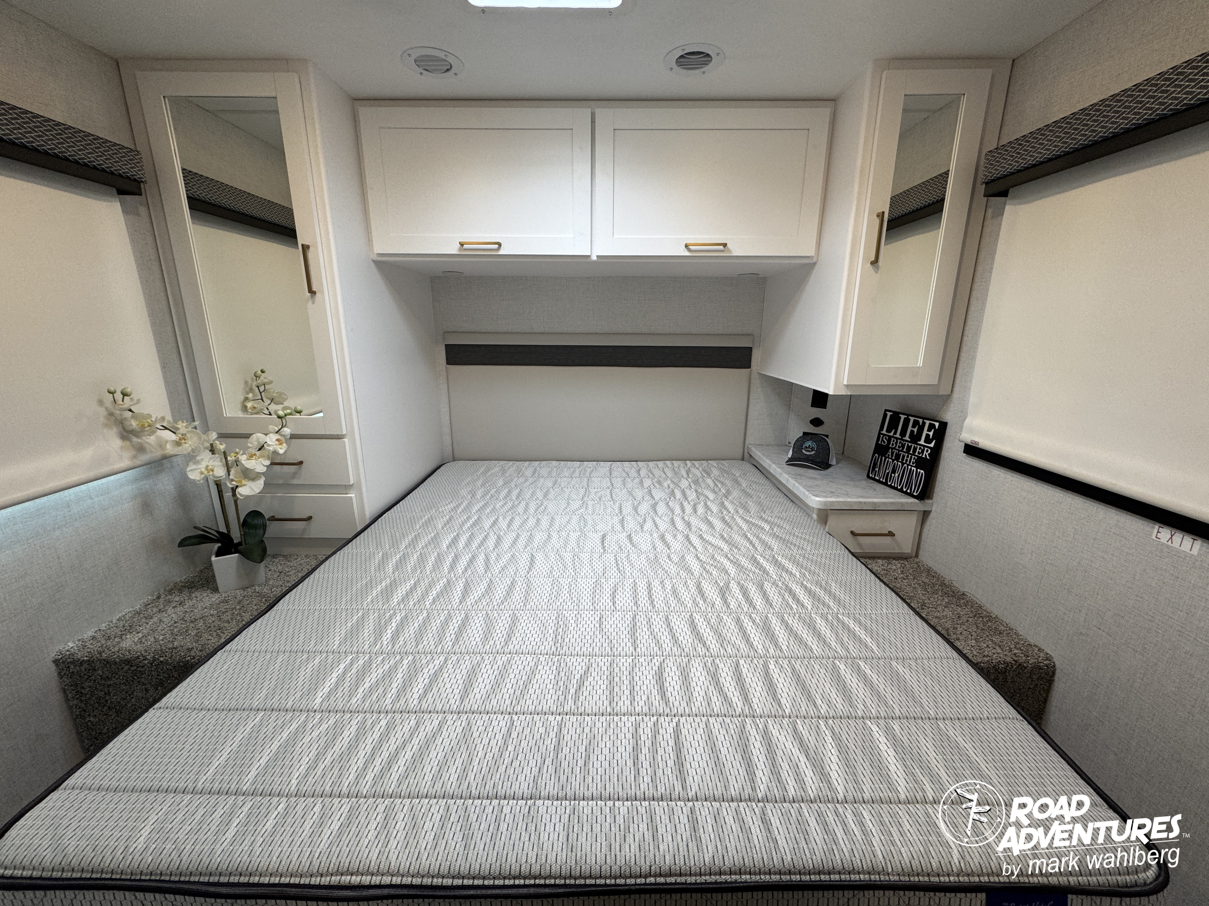 This RV rental bedroom offers a cozy sleeping area with a comfortable bed, overhead storage, and mirrored wardrobes.. Thor Motor Coach Four Winds 28Z 2026