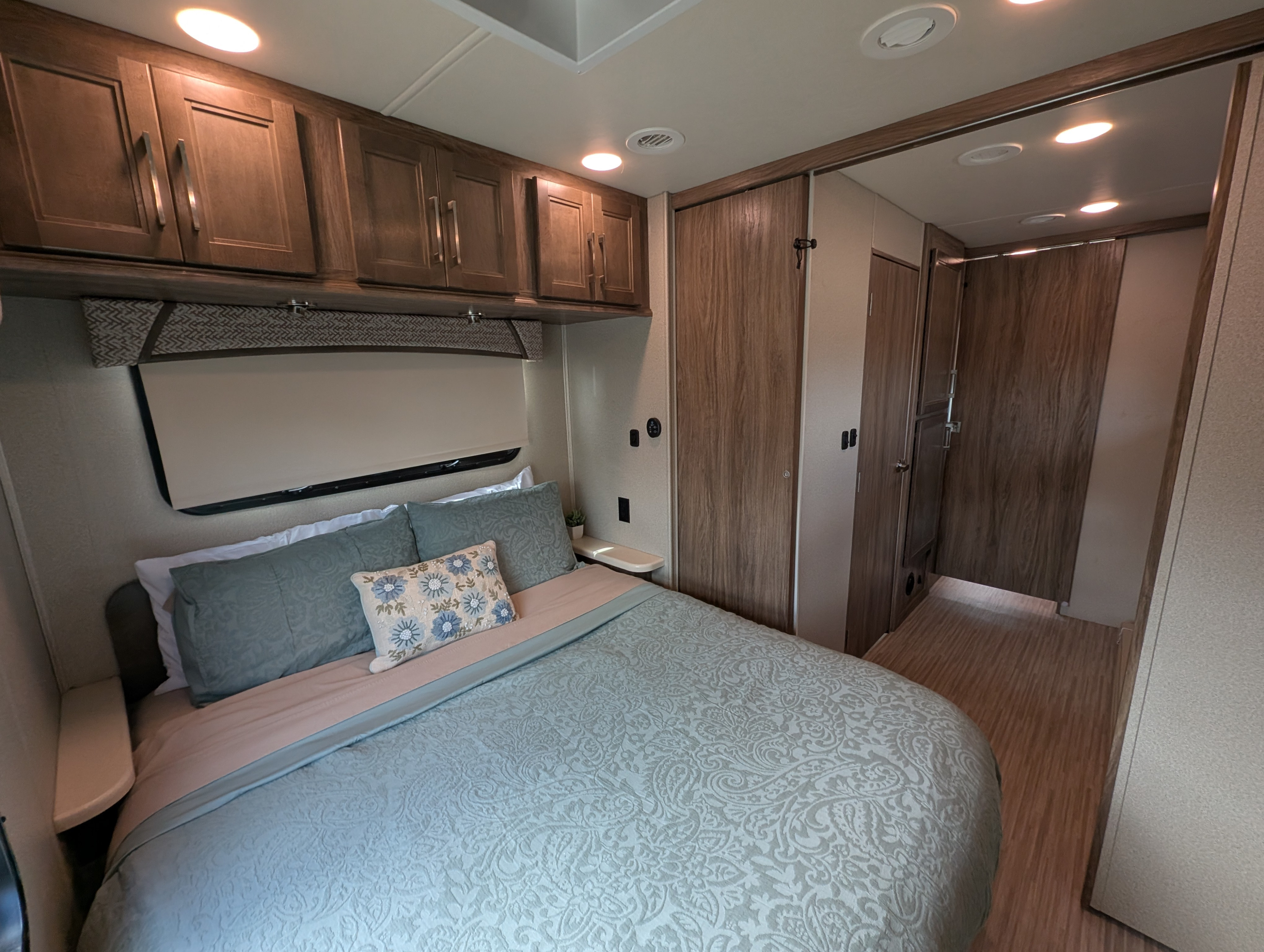 Comfortable RV rental bedroom featuring a neatly made queen bed, sleek overhead cabinets, and wood-look flooring.. Jayco Greyhawk Prestige 2018