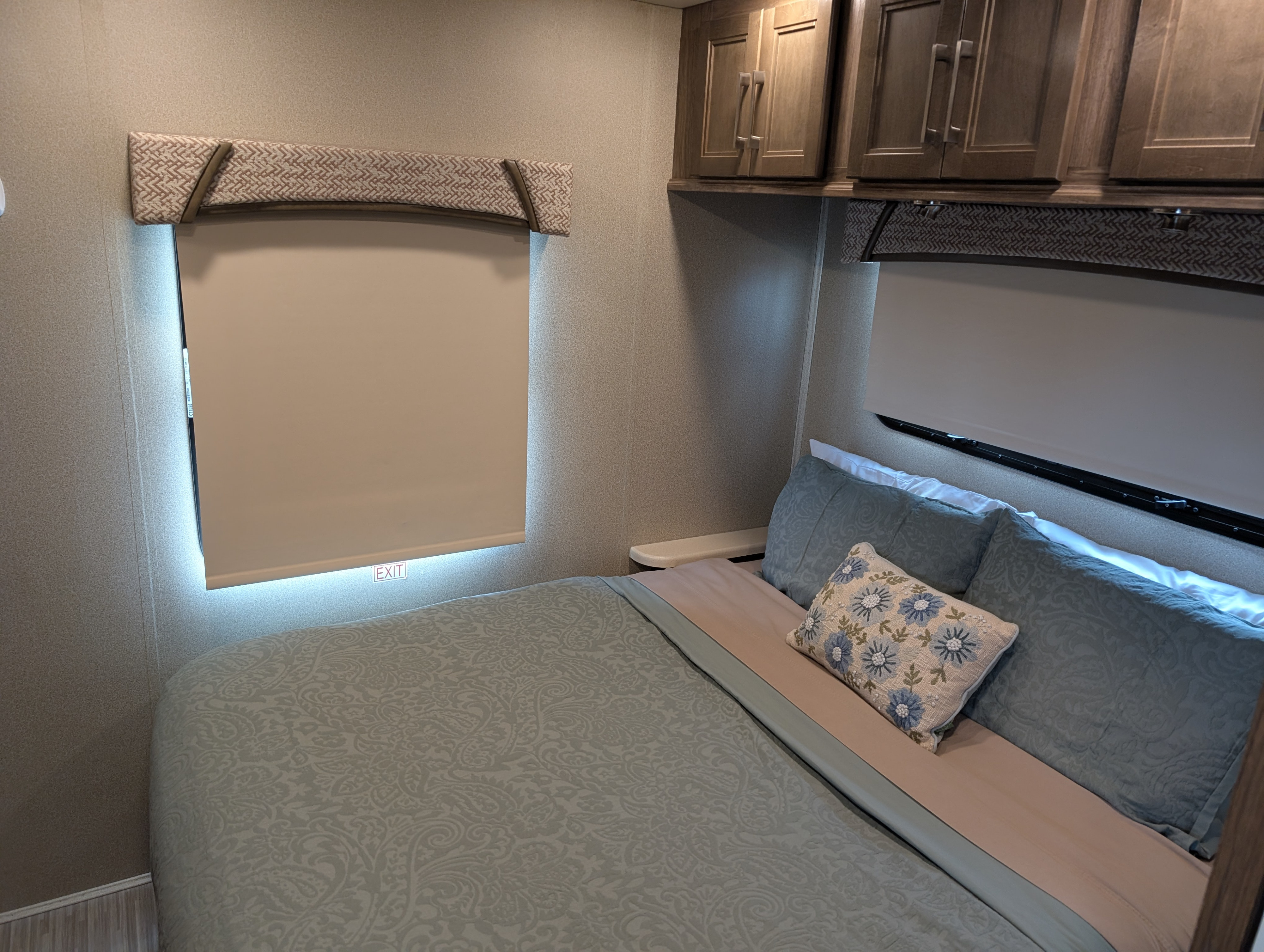 Inside a cozy RV rental: a well-appointed bedroom with a comfy bed, modern cabinetry, and lit window.. Jayco Greyhawk Prestige 2018
