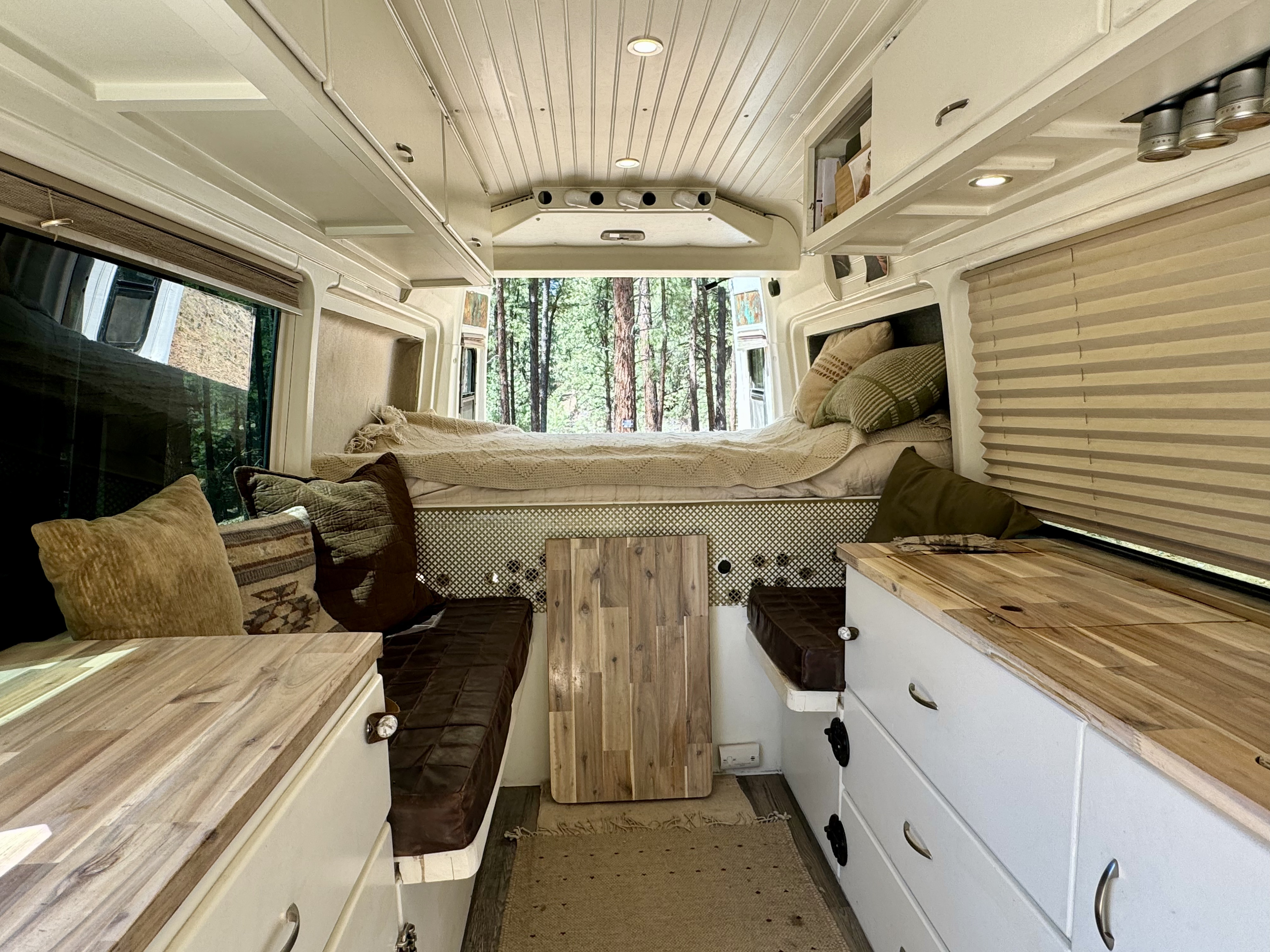 Experience nature from this cozy RV rental's custom interior, featuring a bed, seating, and panoramic forest views.. Dodge Sprinter 2500 170ext 2006
