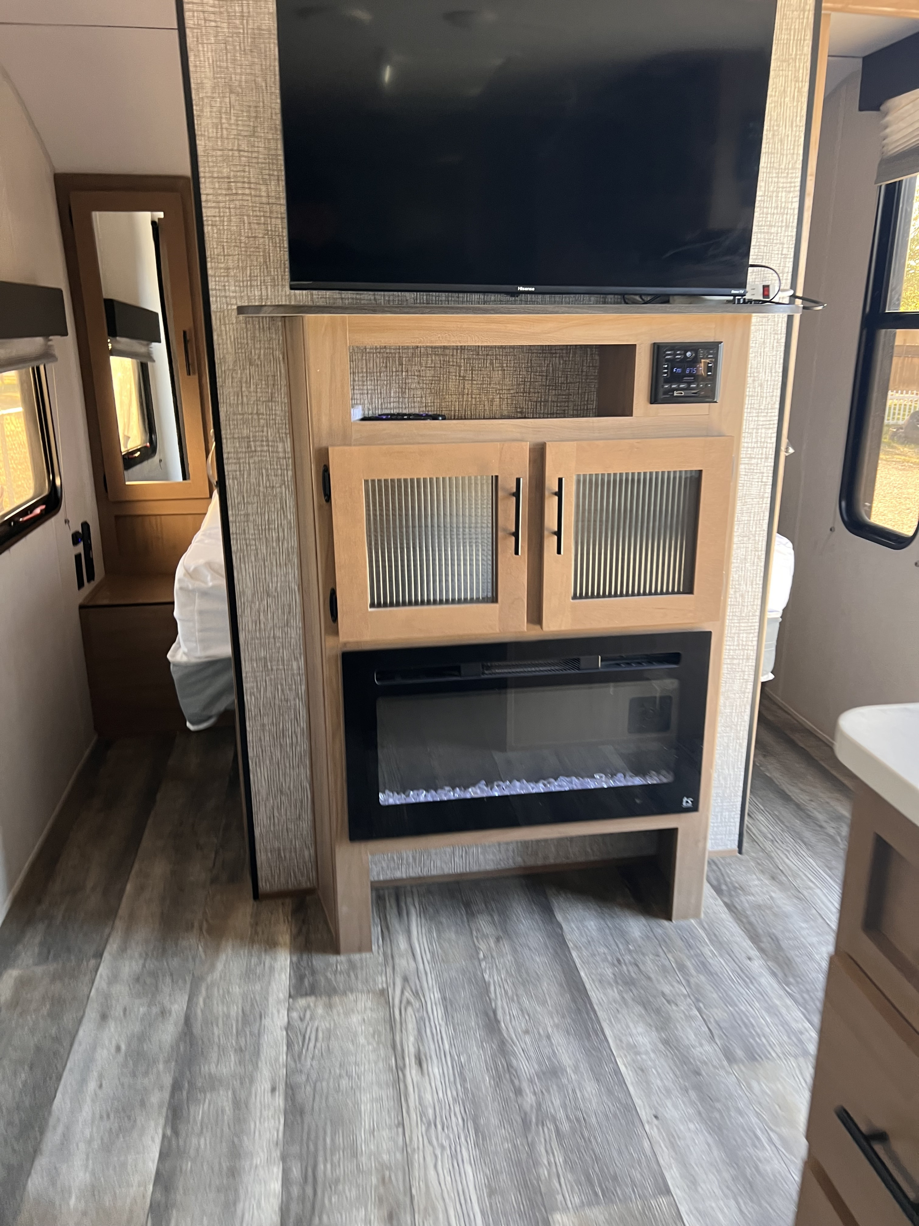 Cozy RV rental interior featuring a Hisense TV, entertainment center with electric fireplace, and wood-look flooring.. Forest River Cherokee Grey Wolf 2023