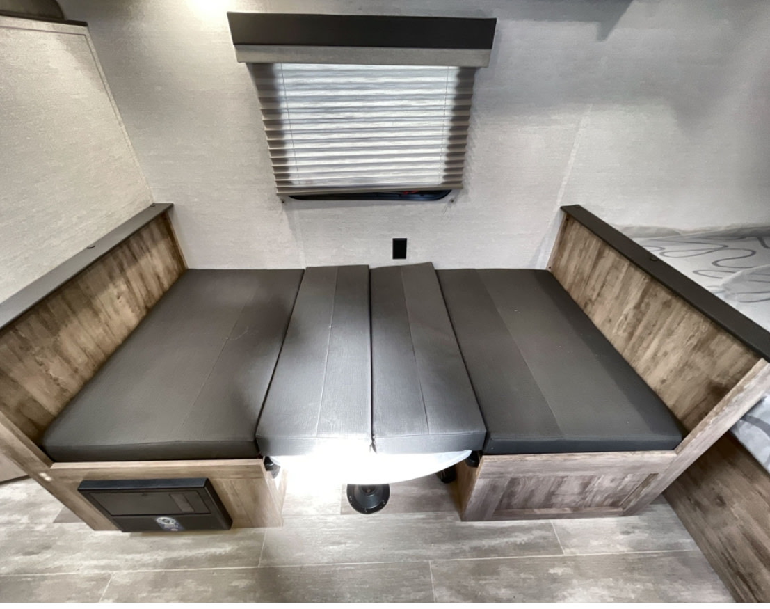 This RV rental features a flexible dinette that easily converts into a comfortable bed. Gray cushions, wood trim, window.. Gulf Stream Enlighten 2025