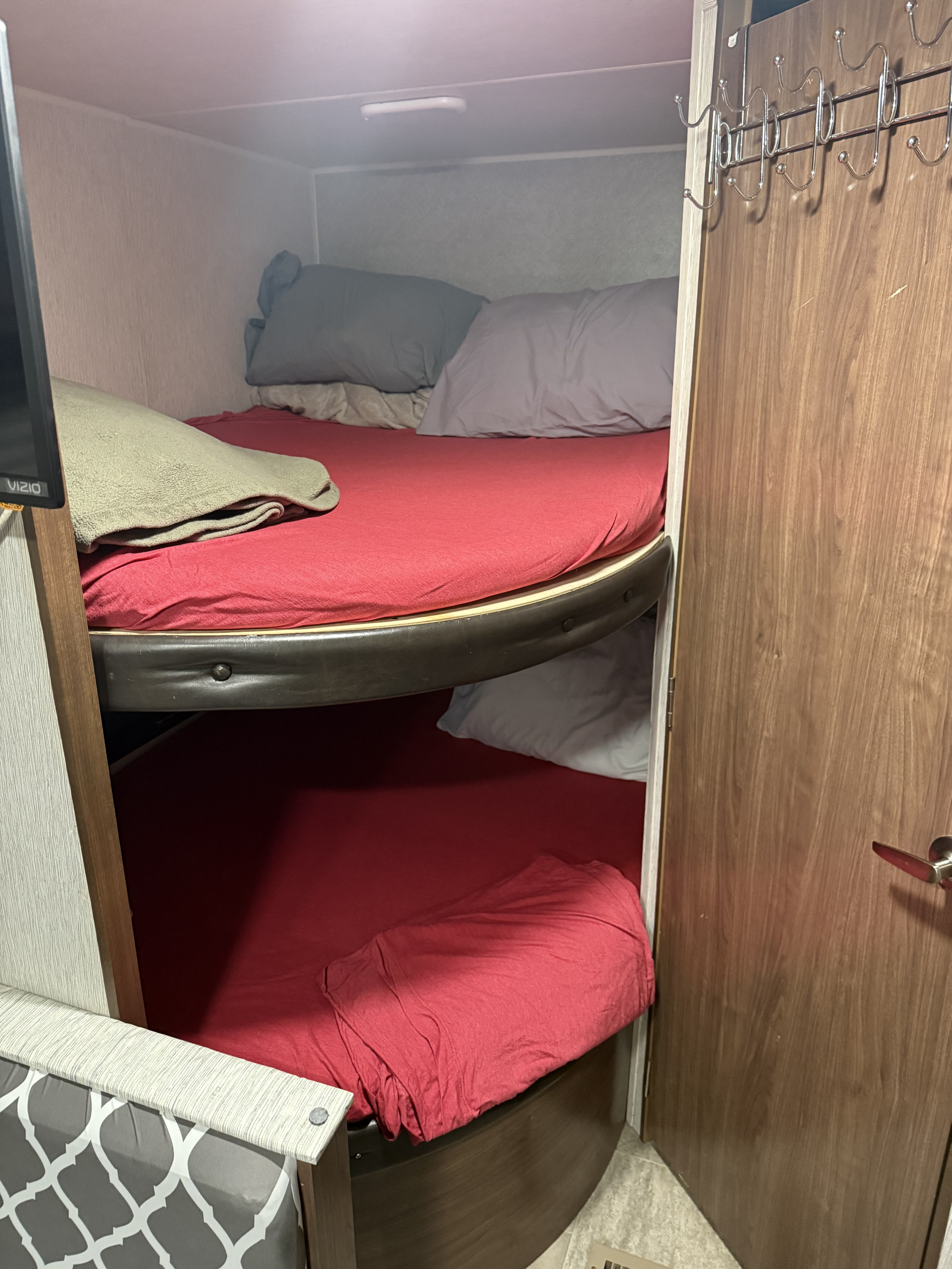 Inside an RV rental: Compact bunk beds featuring red sheets and pillows, ideal for comfortable travel trailer sleeping.. Heartland RVs Trail Runner SLE 2018