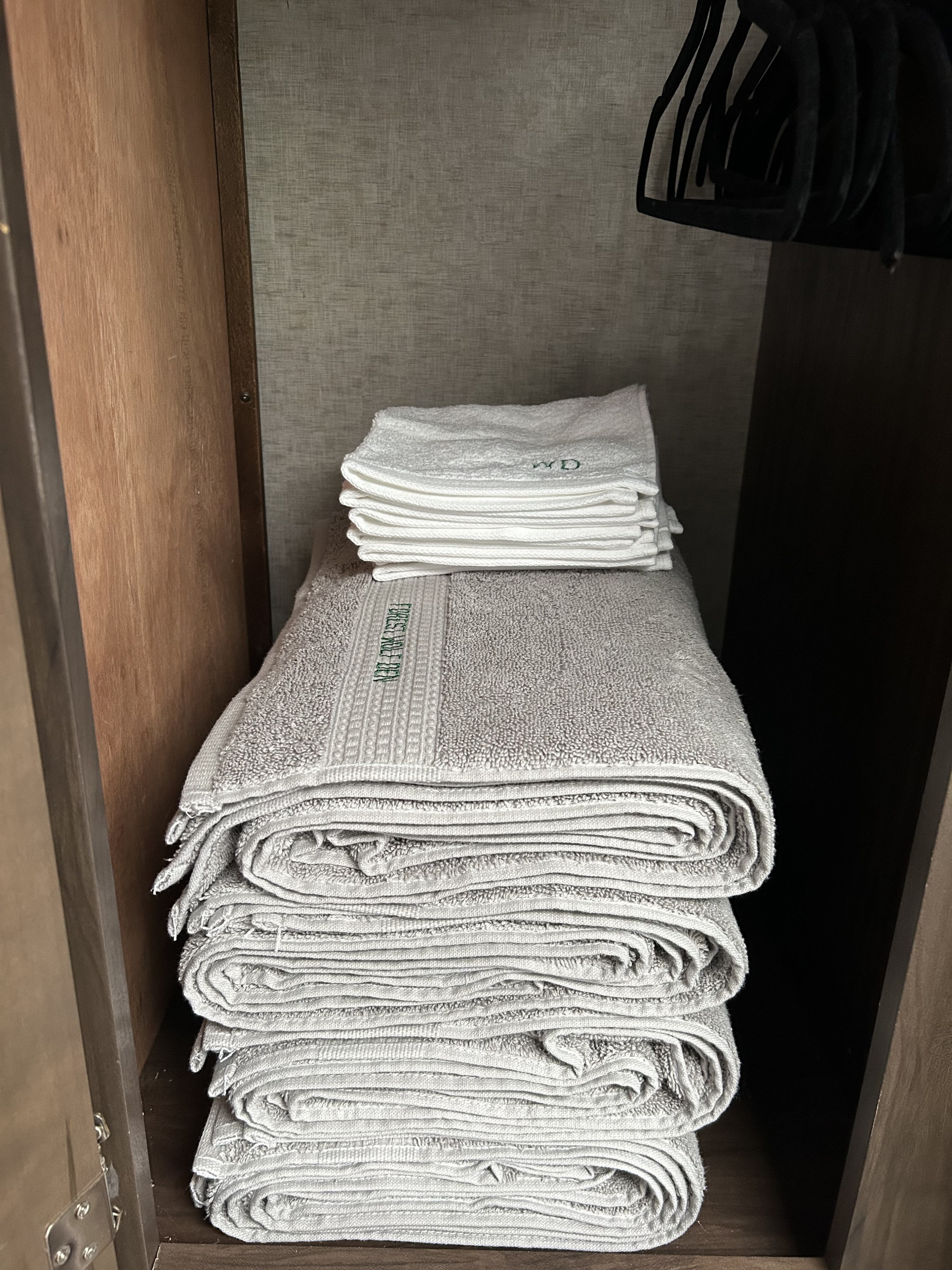Organized RV rental closet: grey "Forest Wolf Den" towels and white "WD" washcloths neatly stacked.. Forest River Cherokee Grey Wolf 2019