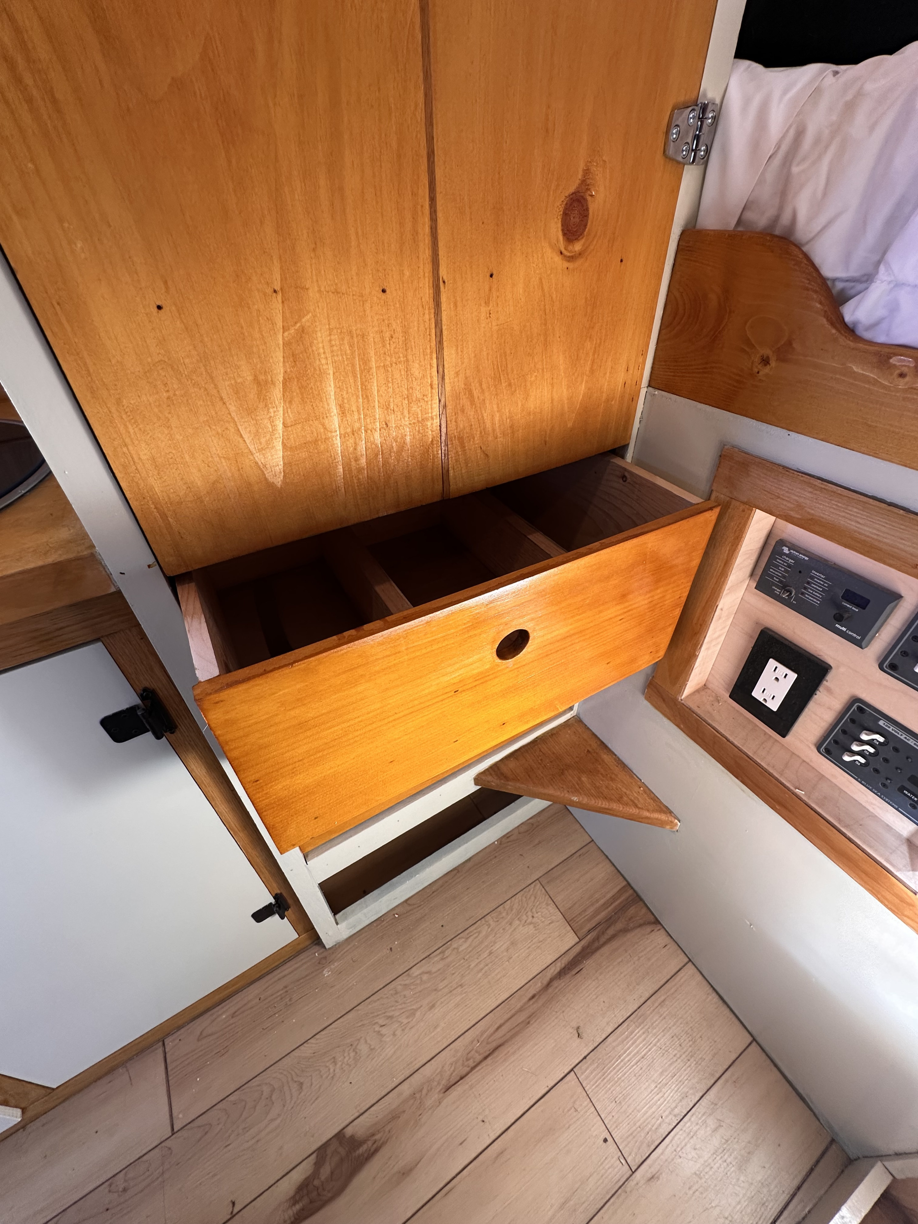 Inside an RV rental: a neat wooden cabinet with an open storage drawer and an integrated electrical control panel.. Mercedes-Benz Sprinter 2022