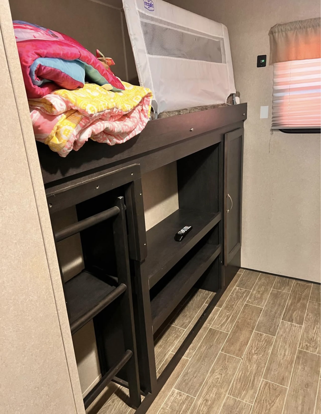 An RV rental features a cozy bunk bed setup with a safety rail, storage shelves, and a window, ideal for family travel.. Palomino 32RBFQ 2019