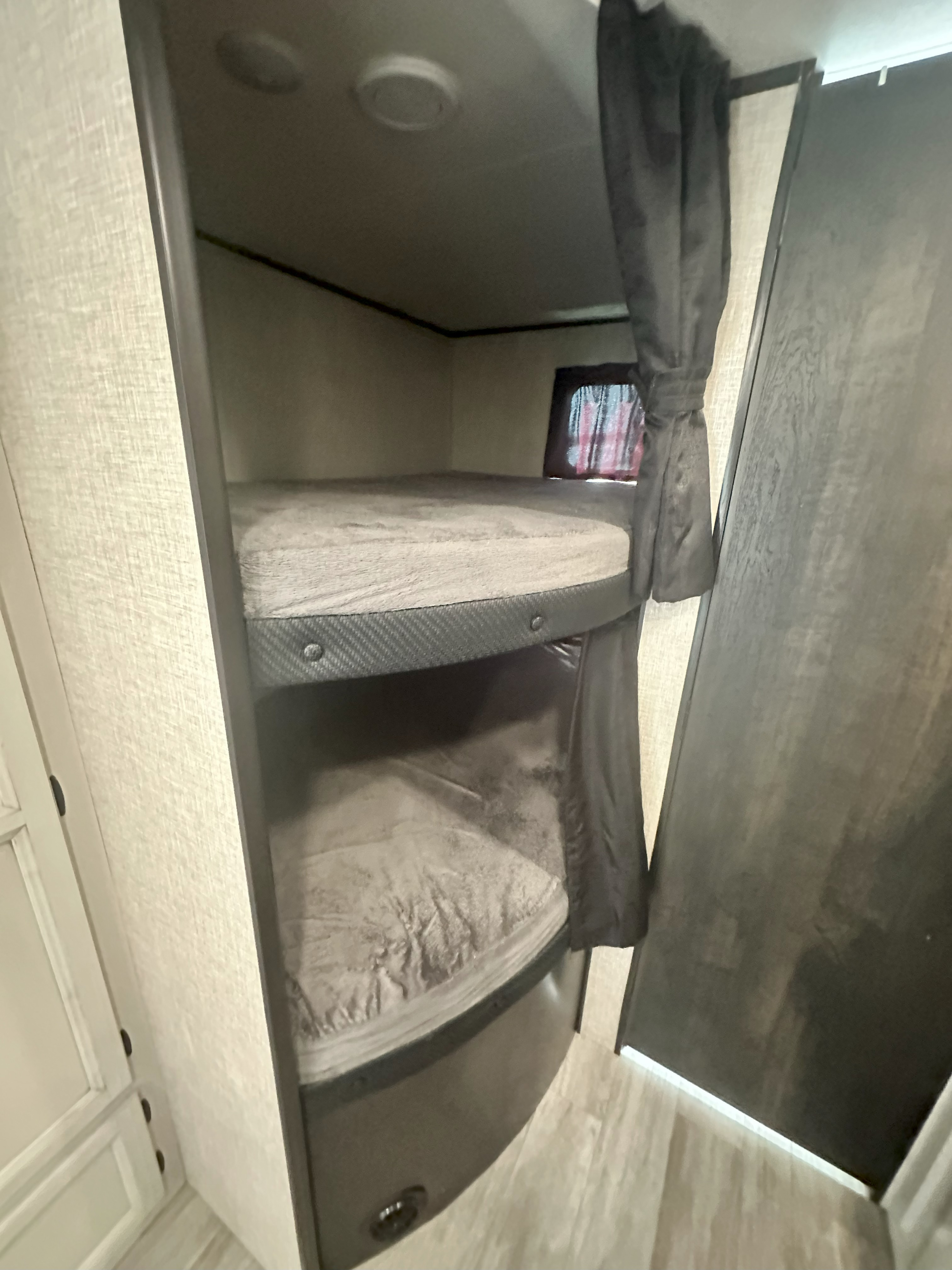 Cozy bunk beds in an RV rental, offering comfortable sleeping for families. Features include a window, curtain, and clean bedding.. Jayco Jay Flight 2022