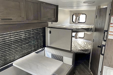 RV rental interior featuring a practical dinette, overhead cabinets, and cozy bunk beds, ideal for family trips.. Forest River Salem FSX 2021