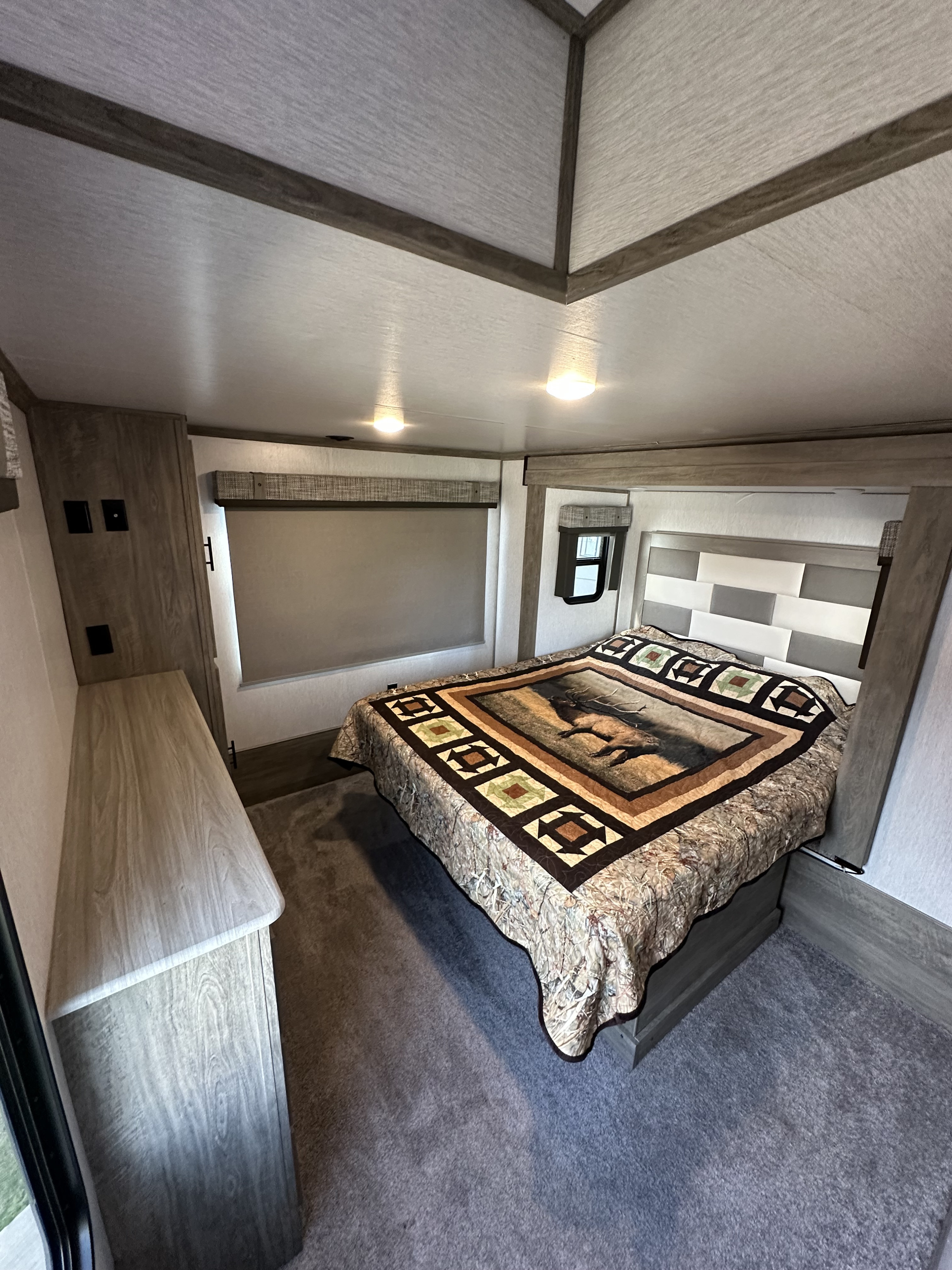 Discover comfort in this RV rental bedroom: cozy bed with elk quilt, modern headboard, and ample storage.. Forest River Salem Hemisphere 2022