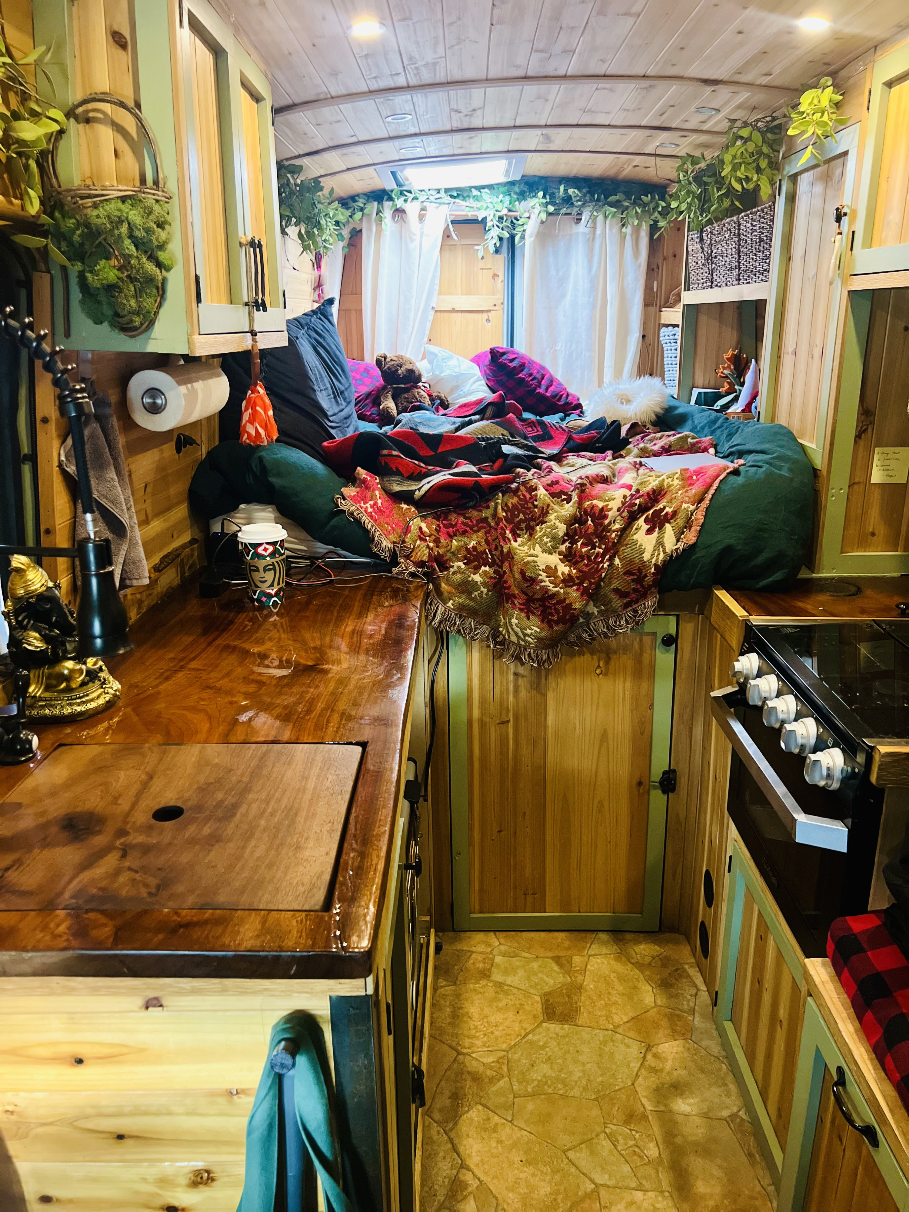 Cozy custom RV rental interior: comfortable bed, rustic kitchenette, ample storage, and warm wood details for tiny living.. Ford Transit 2015