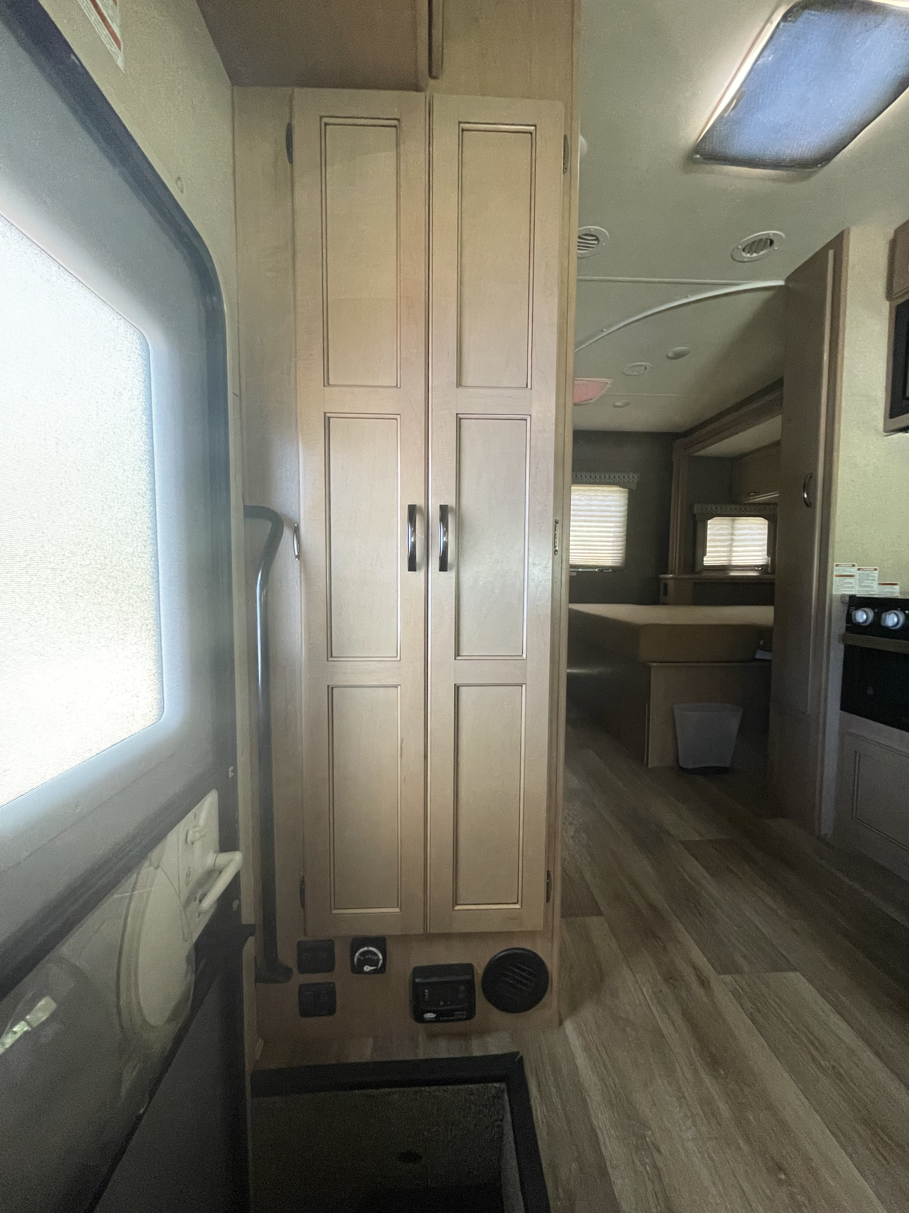 RV rental interior featuring a bright window, central storage cabinets, and a peek into the bedroom area.. Thor Motor Coach Freedom Elite 2019