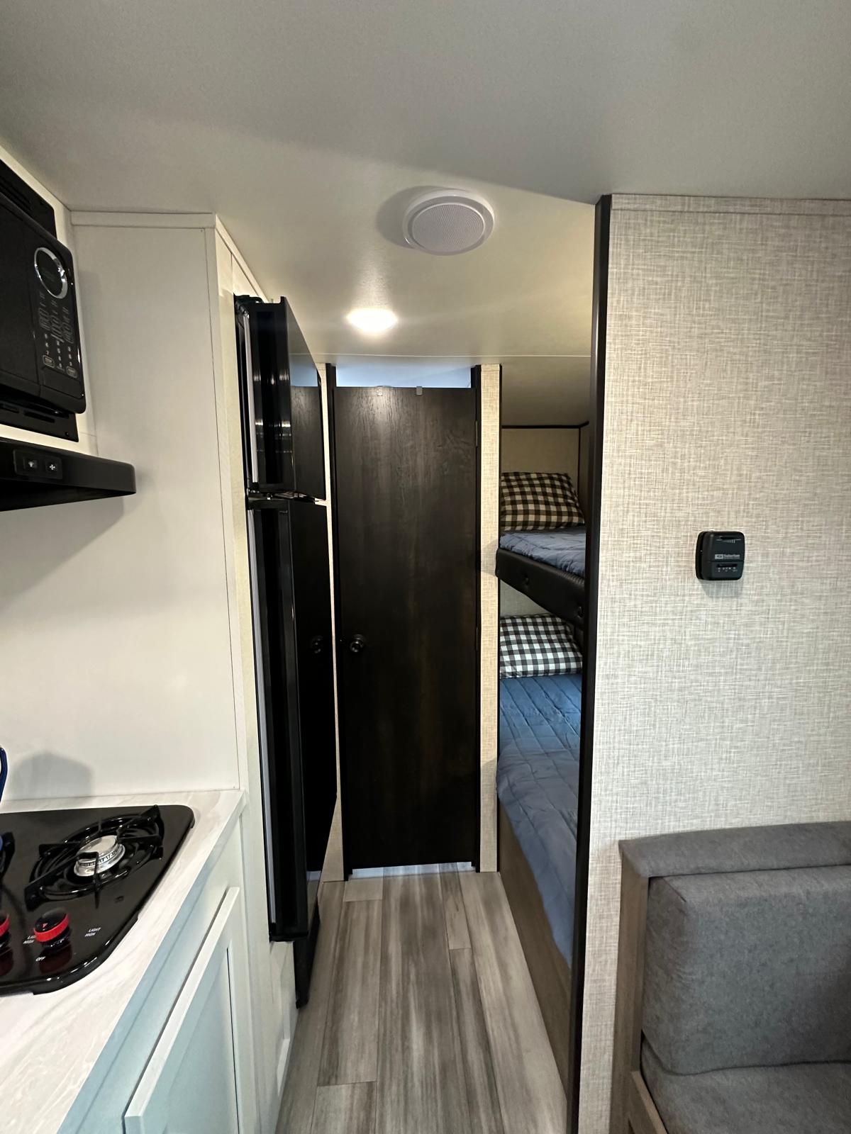 RV rental interior features kitchen, refrigerator, bunk beds, and seating. Compact design for comfortable travel.. Jayco Jay Flight SLX 2024