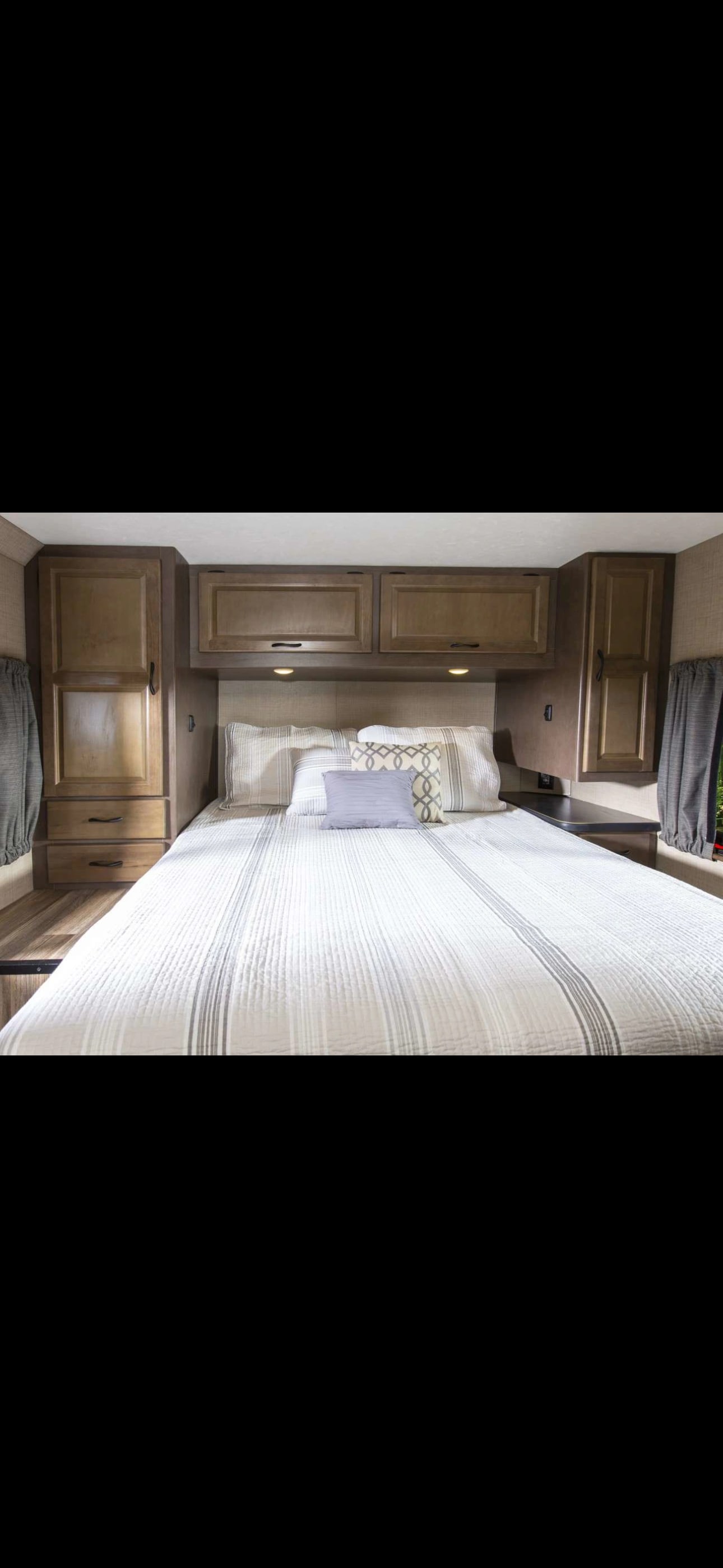 Cozy RV rental bedroom with comfortable bed, storage cabinets, and warm lighting. Ideal for your next adventure.. Thor Majestic 2020