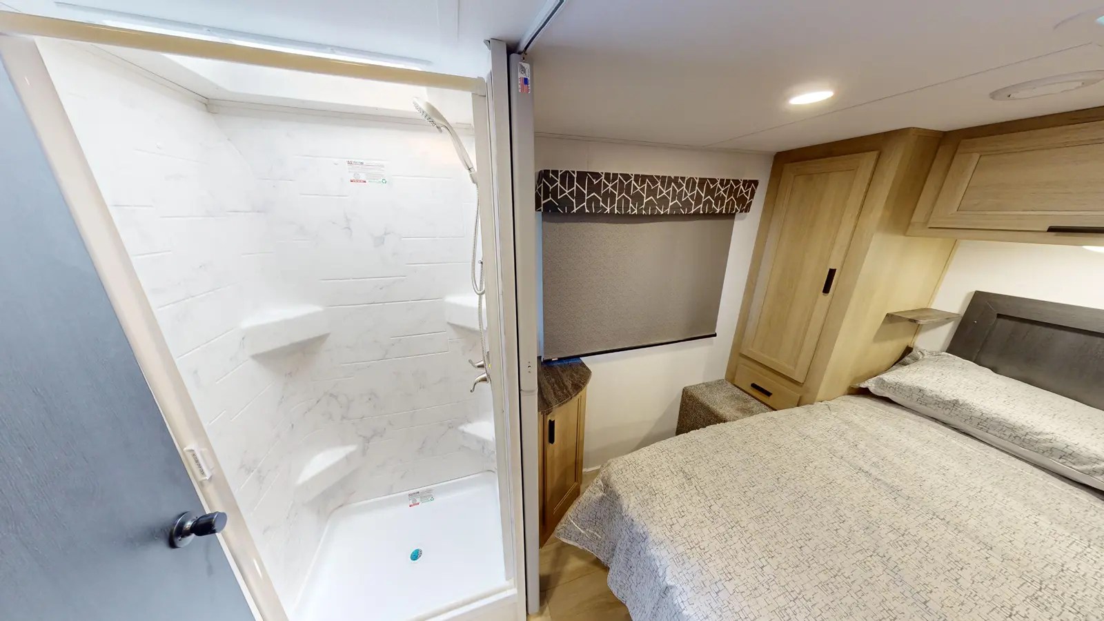 Inside this RV rental: a bright shower with a built-in shelf and a bedroom area with a comfy bed, cabinets, and window.. Forest River SUNSEEKER 2850 2026