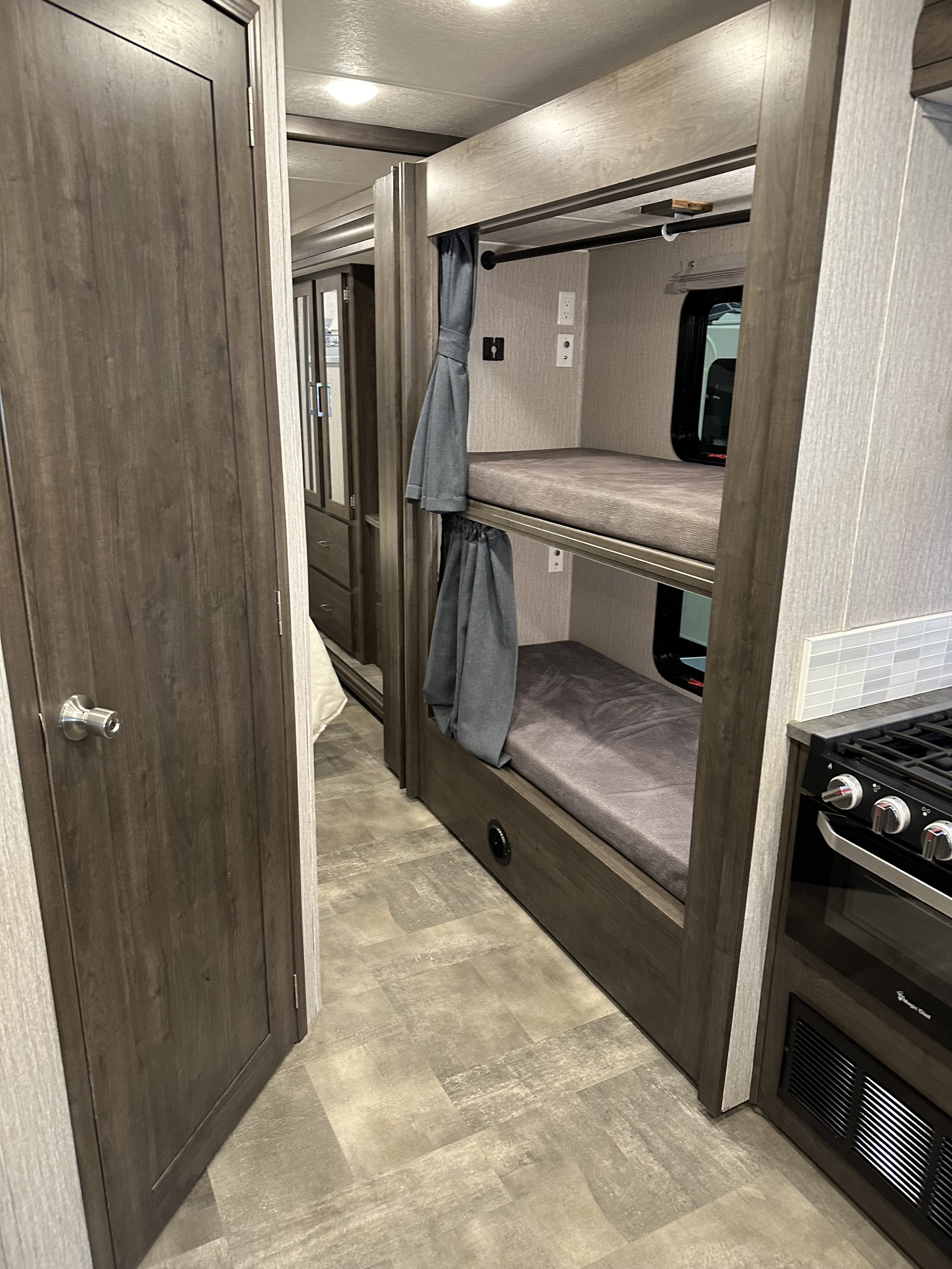 Inside an RV rental, featuring a practical layout with cozy bunk beds on the right, and a glimpse of the kitchen.. Coachmen Pursuit 2023