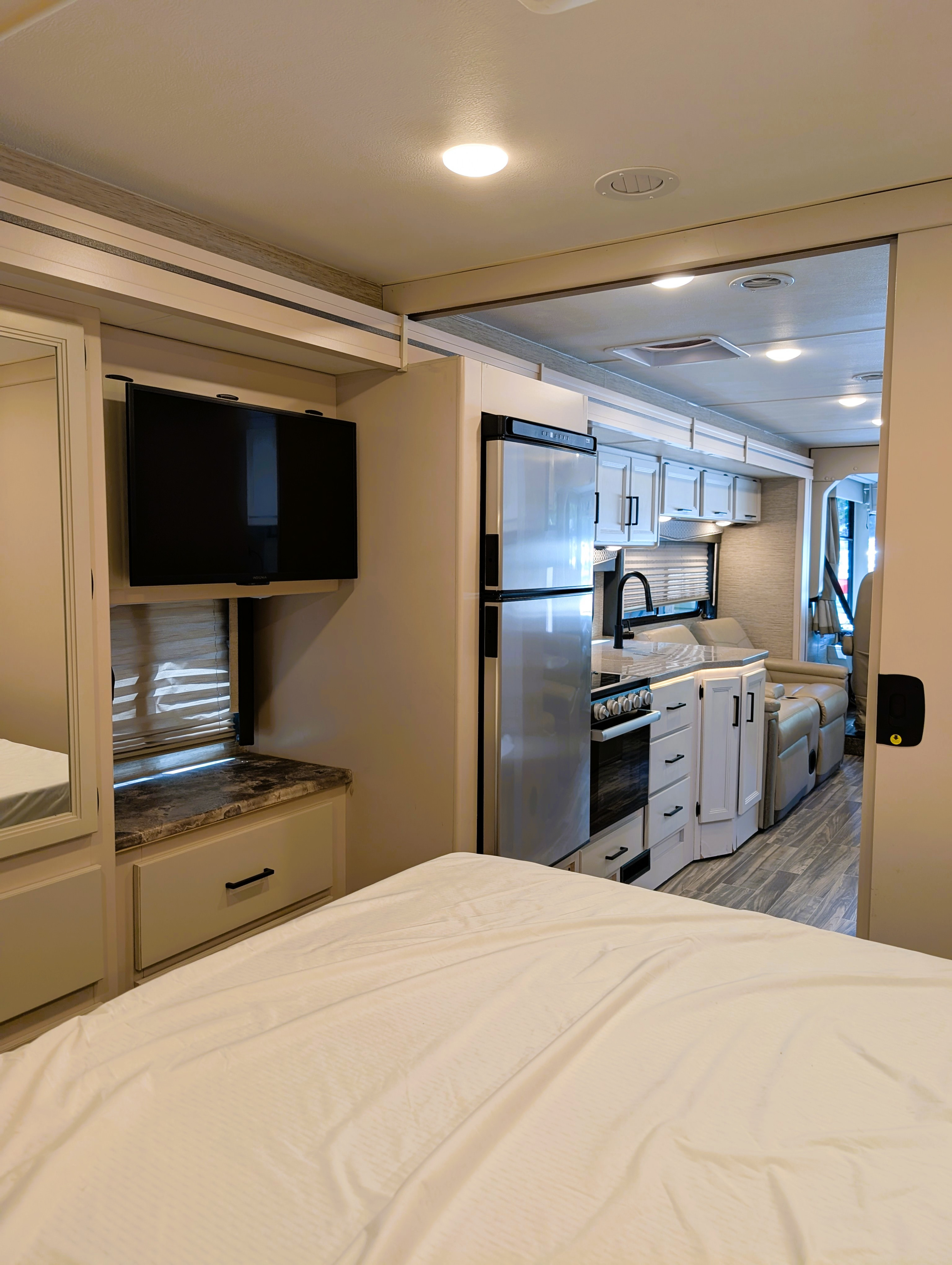 Clean RV rental showcasing a bedroom with TV, a modern kitchen, and a comfortable living space.. Thor Motor Coach A.C.E 2023