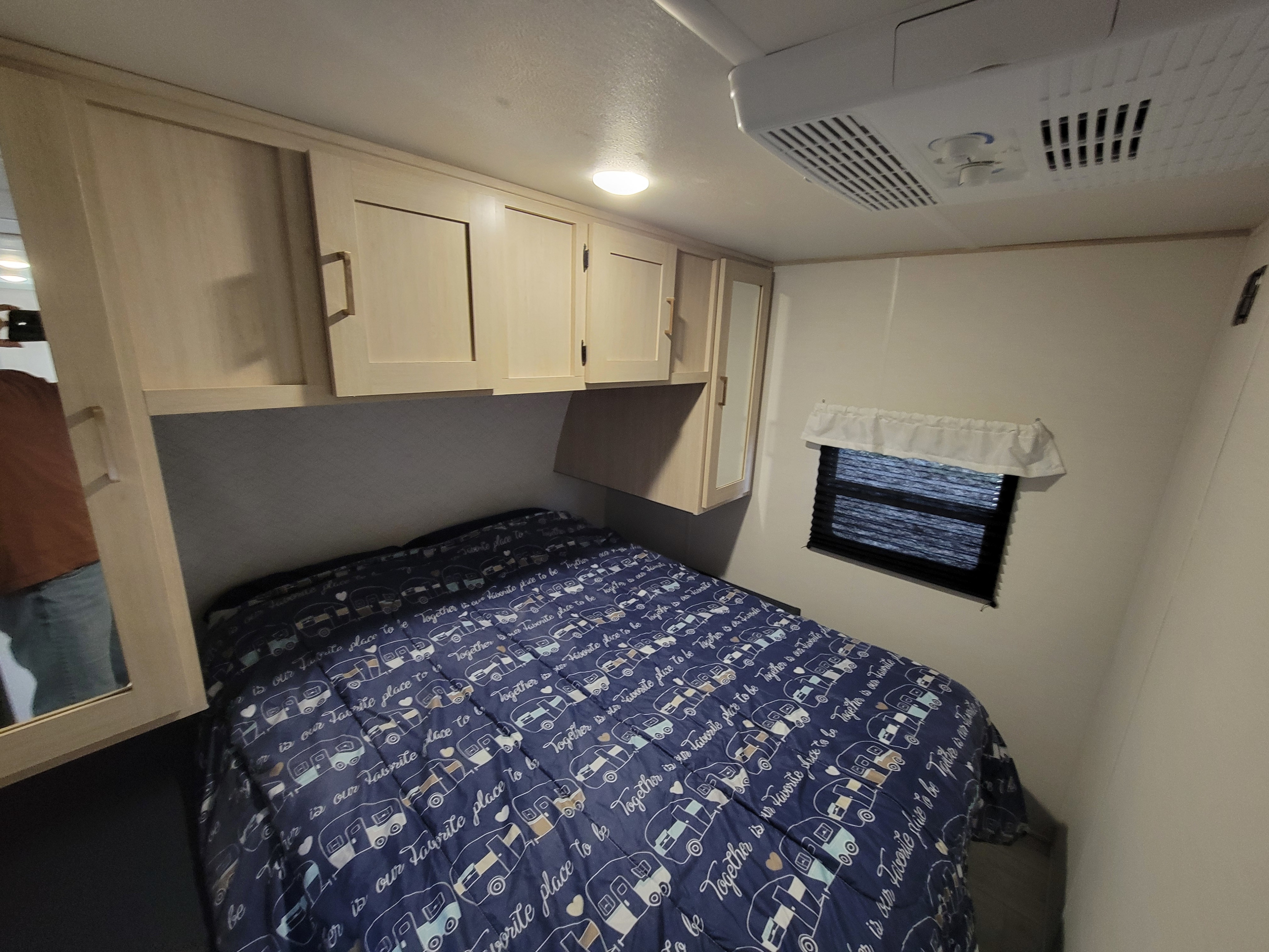 Cozy RV rental bedroom featuring a comfy bed, overhead storage, a window, and an AC unit.. Forest River Avenger Prime Time 2024