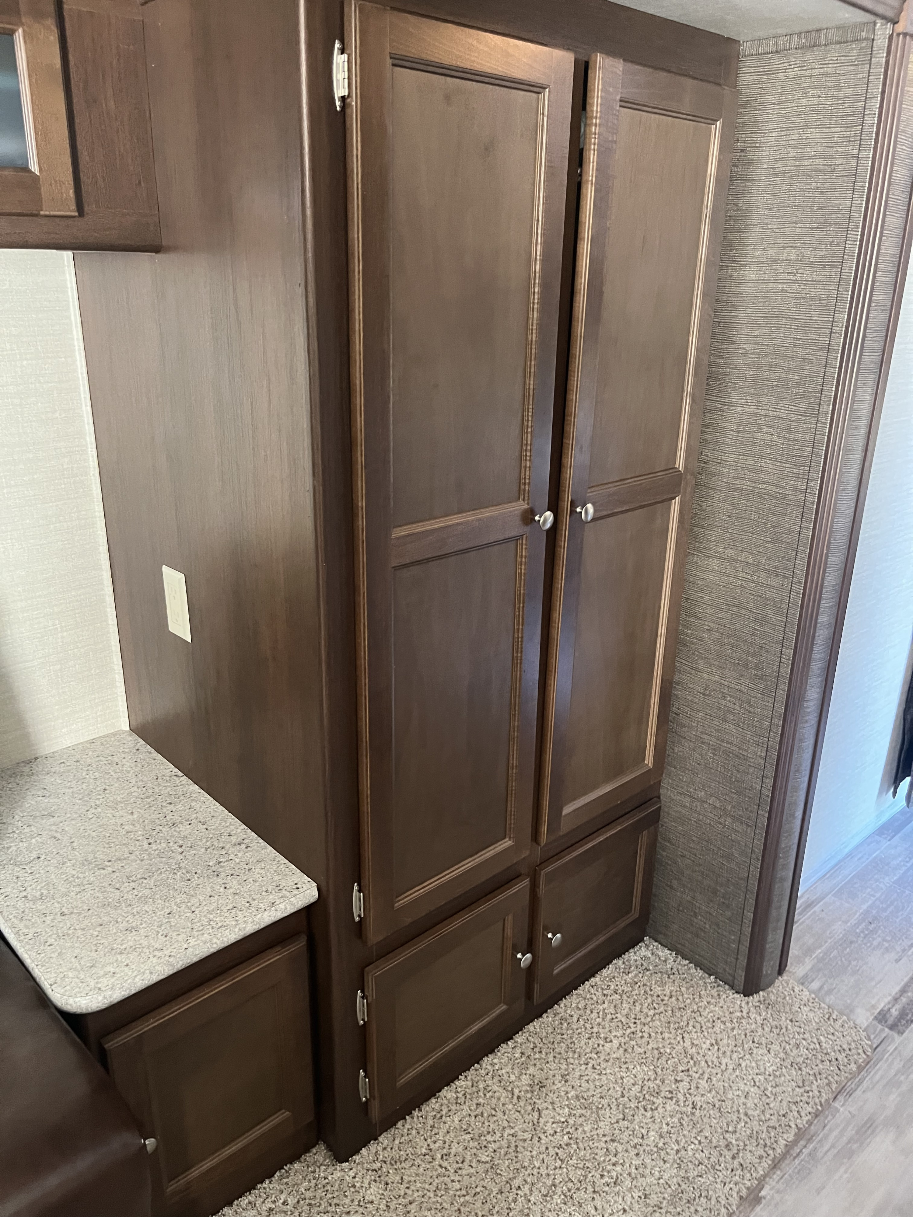 RV rental interior showcases dark wood cabinets, a tall wardrobe, light counter space, and soft carpet.. Keystone RV Bullet Ultra Lite 2015