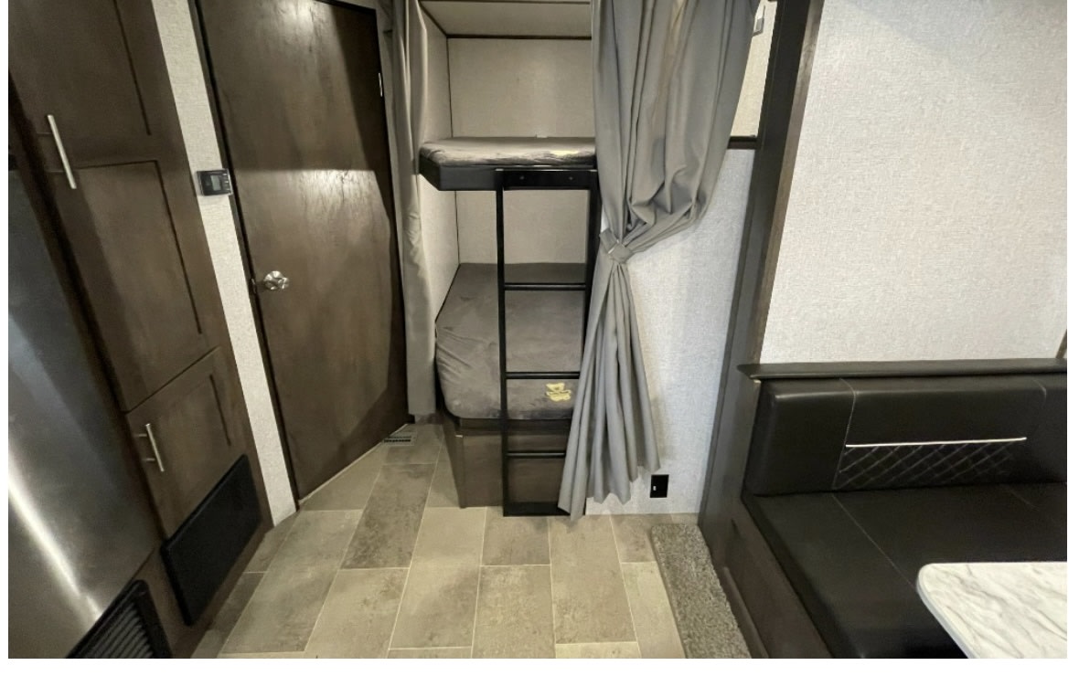 RV rental interior with comfortable bunk beds, a ladder, and a cozy dinette area for your next adventure.. Coleman Lantern 2021