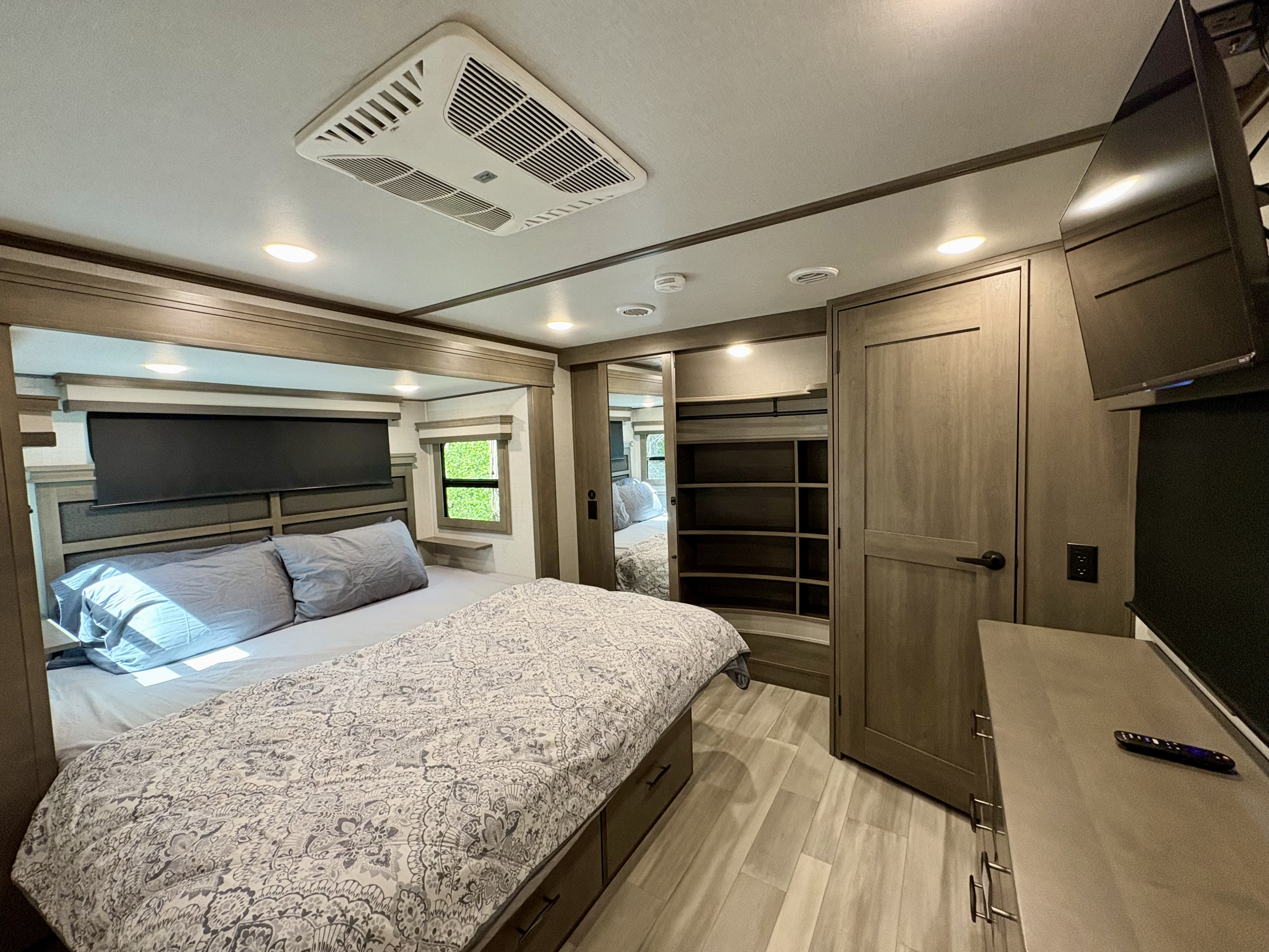 Spacious RV rental bedroom with comfy bed, ceiling AC, built-in storage & TV. Perfect for a relaxing getaway.. Grand Design Solitude 2023