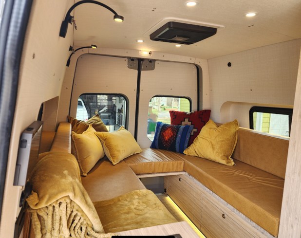 Experience comfort in this custom RV rental interior. Plush mustard cushions and thoughtful lighting create a cozy lounge space.. Mercedes Sprinter 2021