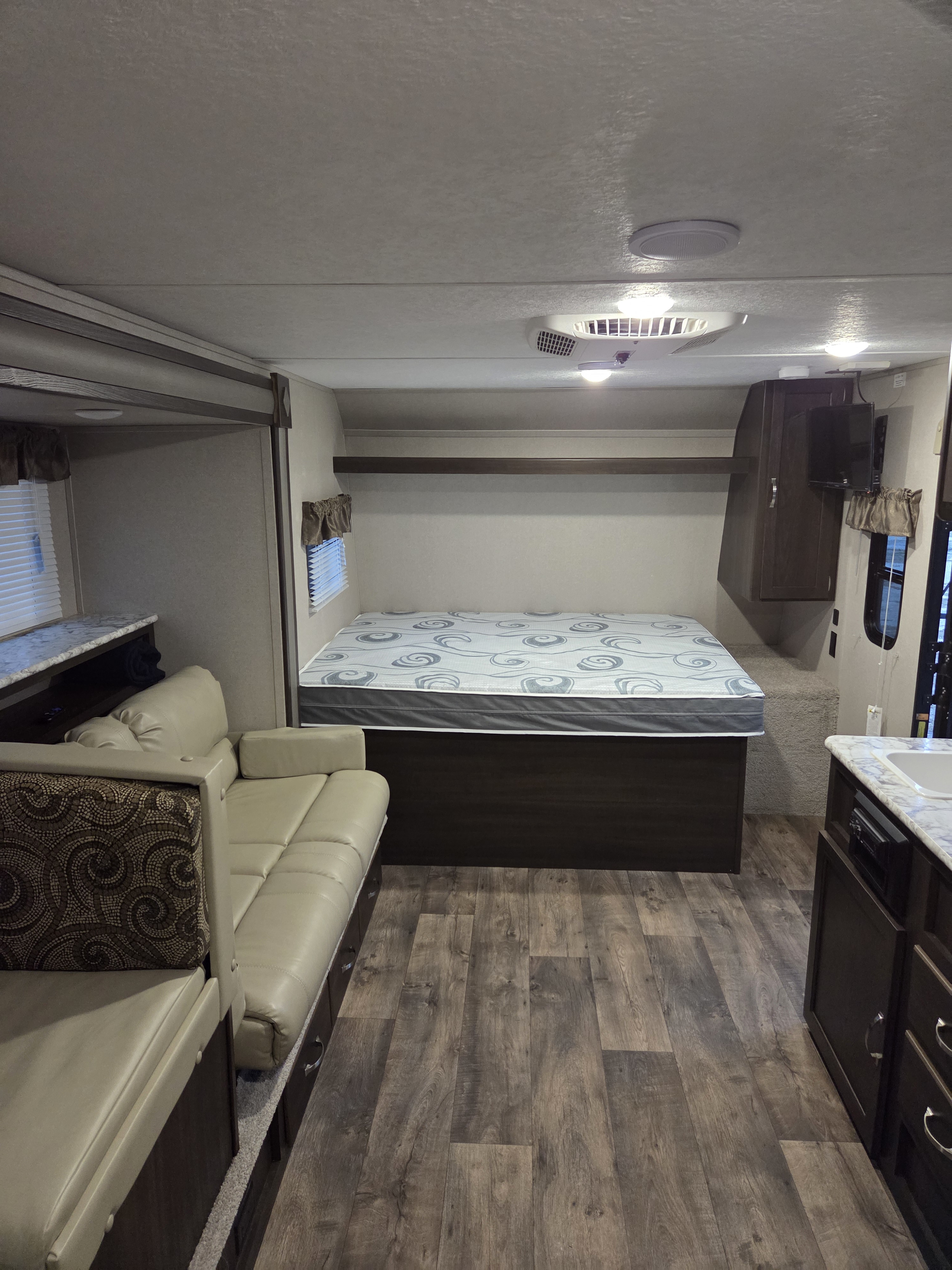 Cozy RV rental interior with a bed, dinette seating, and compact kitchen setup.. Keystone RV Springdale 2019