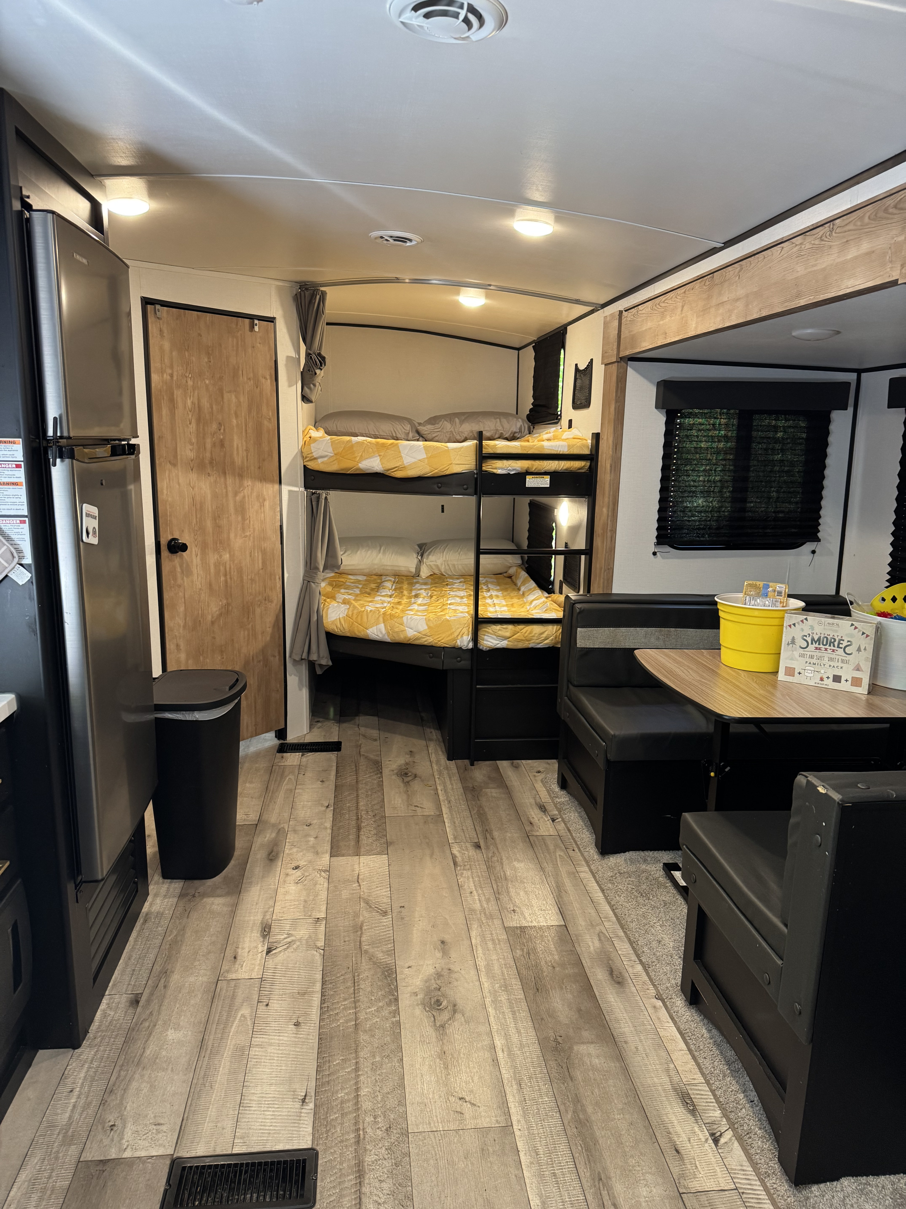 Cozy RV rental interior featuring bunk beds, a dinette, and a refrigerator, ideal for comfortable family travels.. Keystone RV Springdale 2022