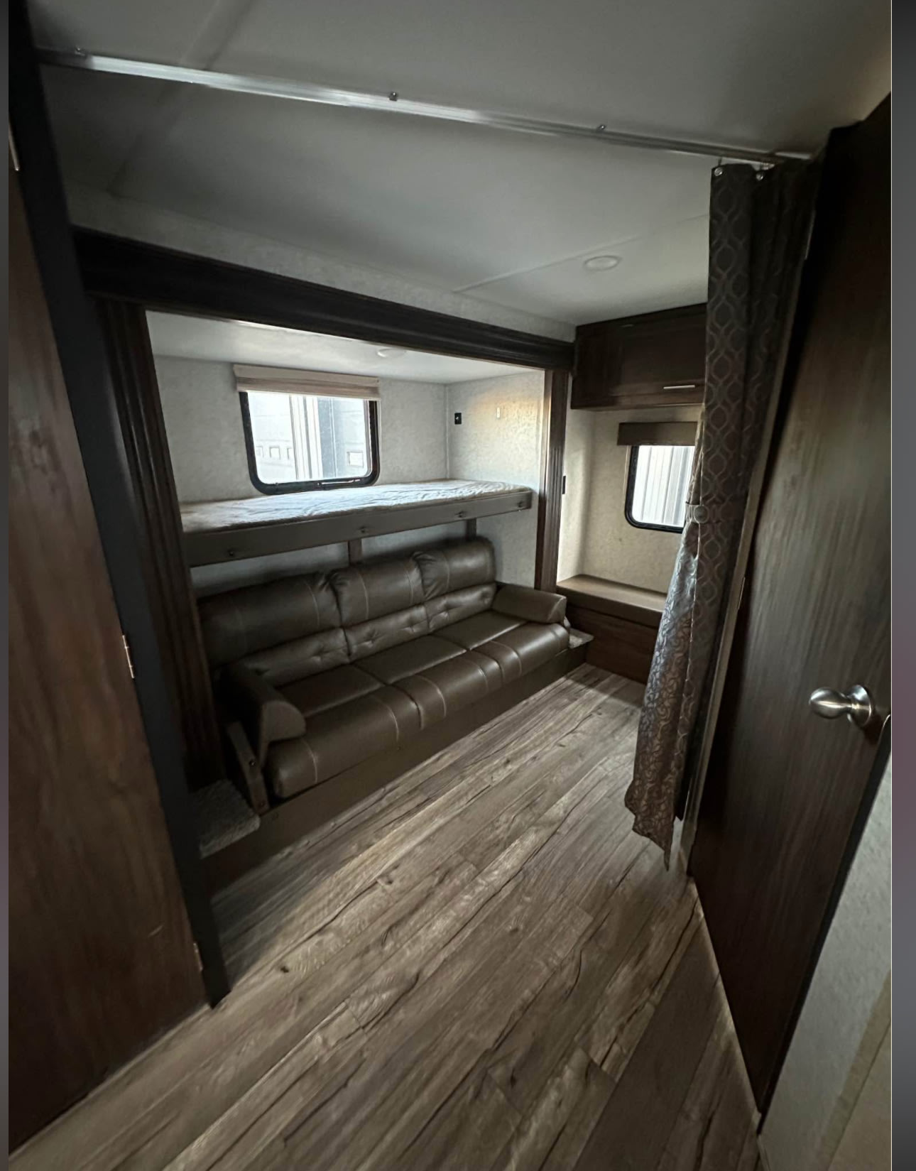 RV rental interior: brown sofa and bunk bed on wood-look floors, offering cozy living and sleeping space.. Forest River Cherokee Grey Wolf 2018